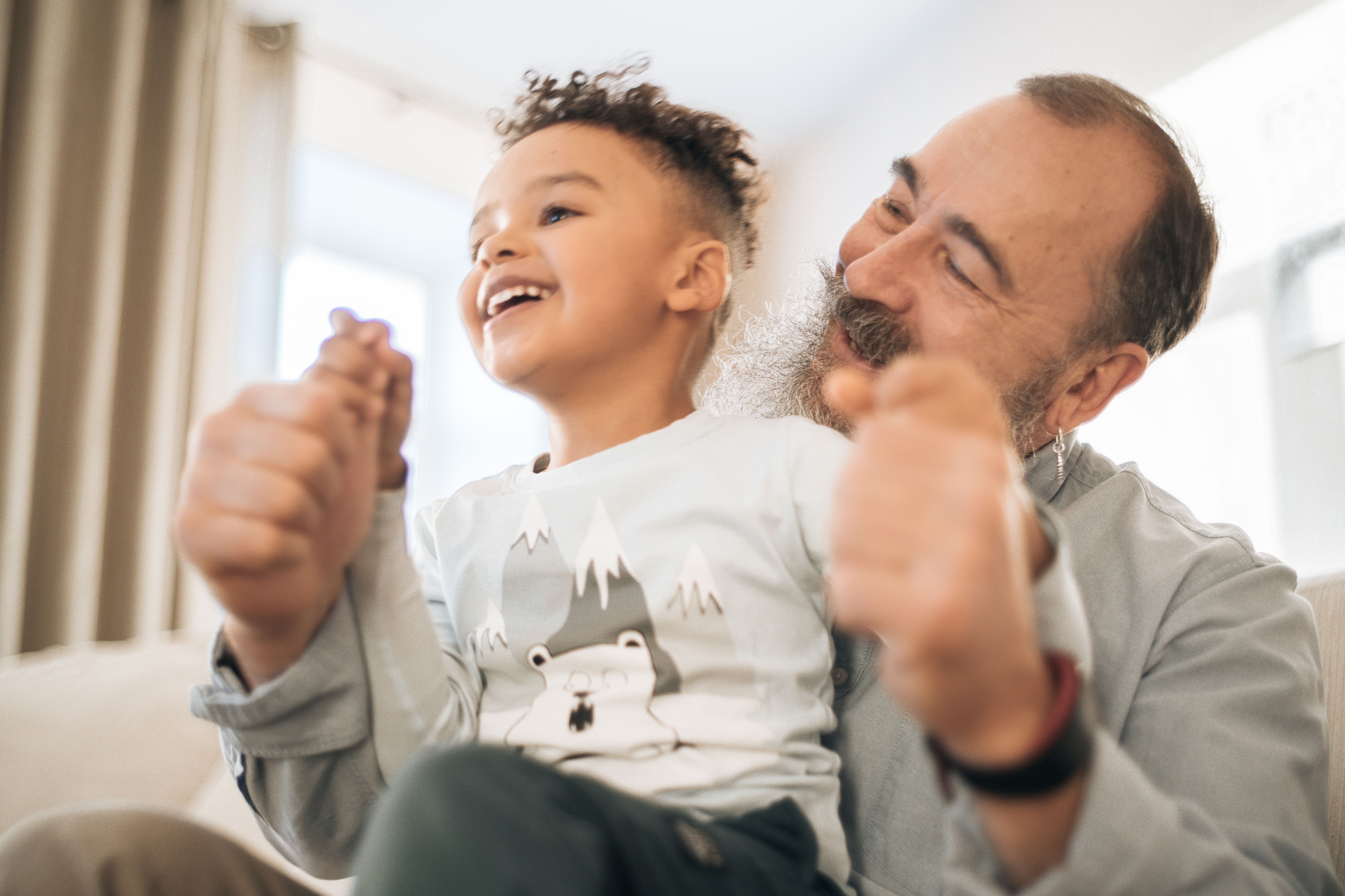 Grandfather and young boy laughing and playing together indoors