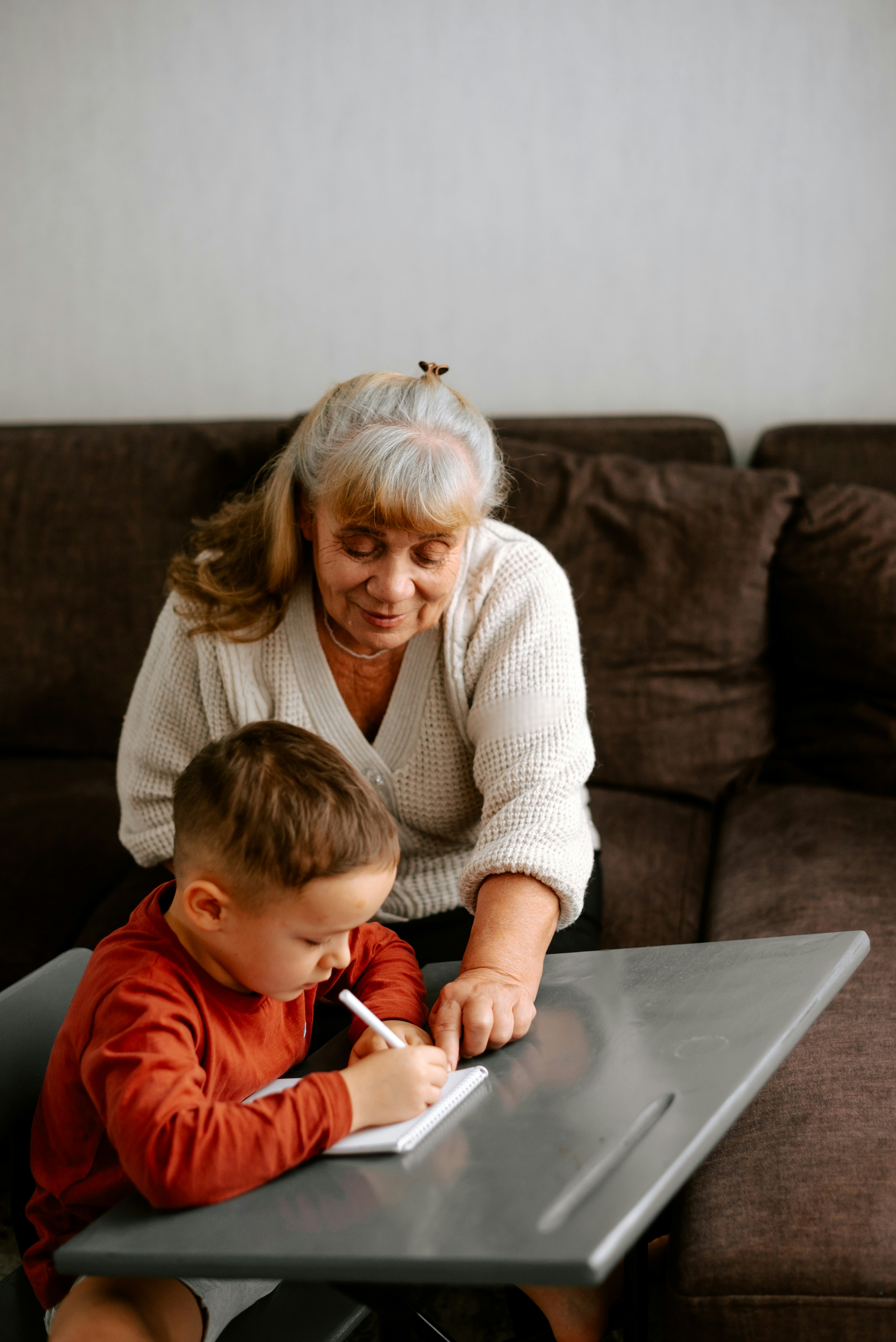 Elderly woman helping a young boy with writing at a table
