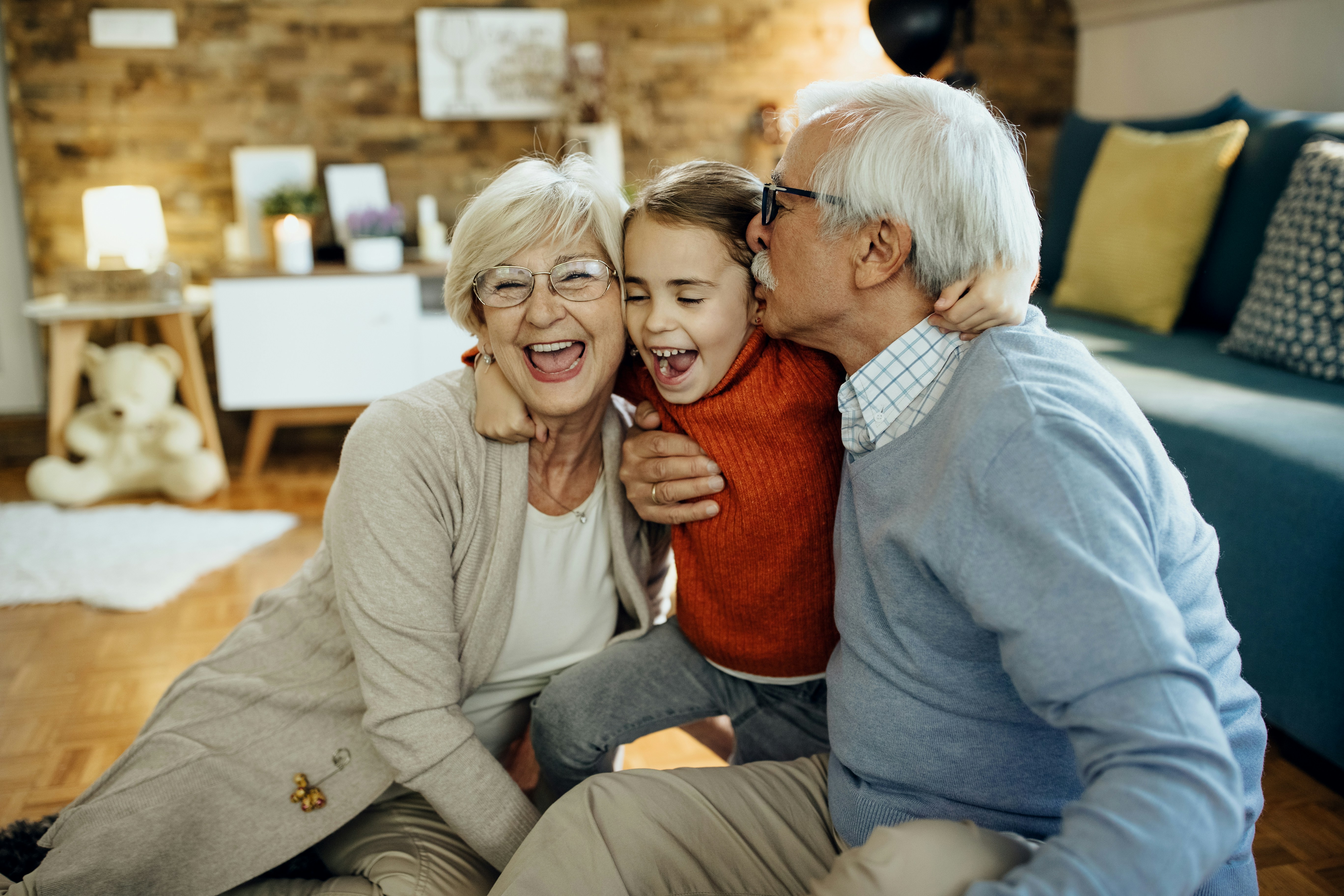 Happy grandparents hugging their grandchild in a cozy living room
