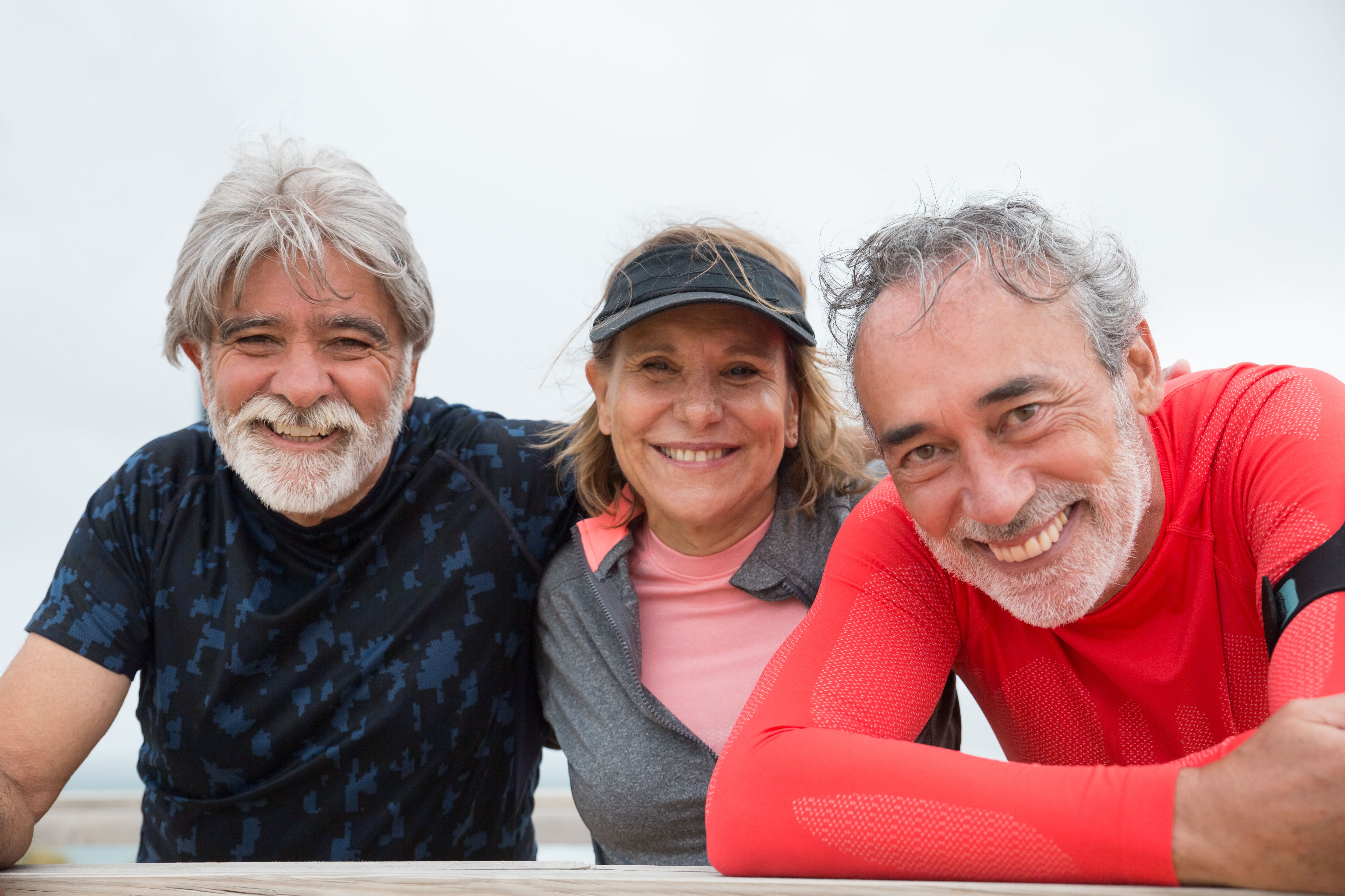 Three smiling older adults enjoying time outdoors together