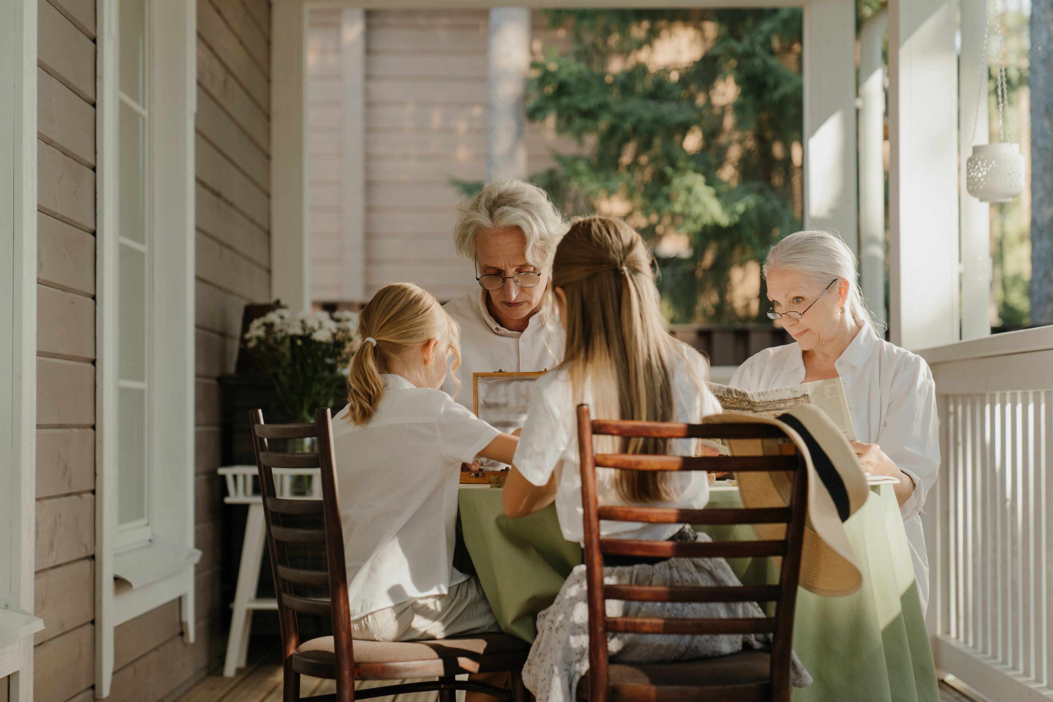 Family with grandparents and children sitting at a table on a porch.