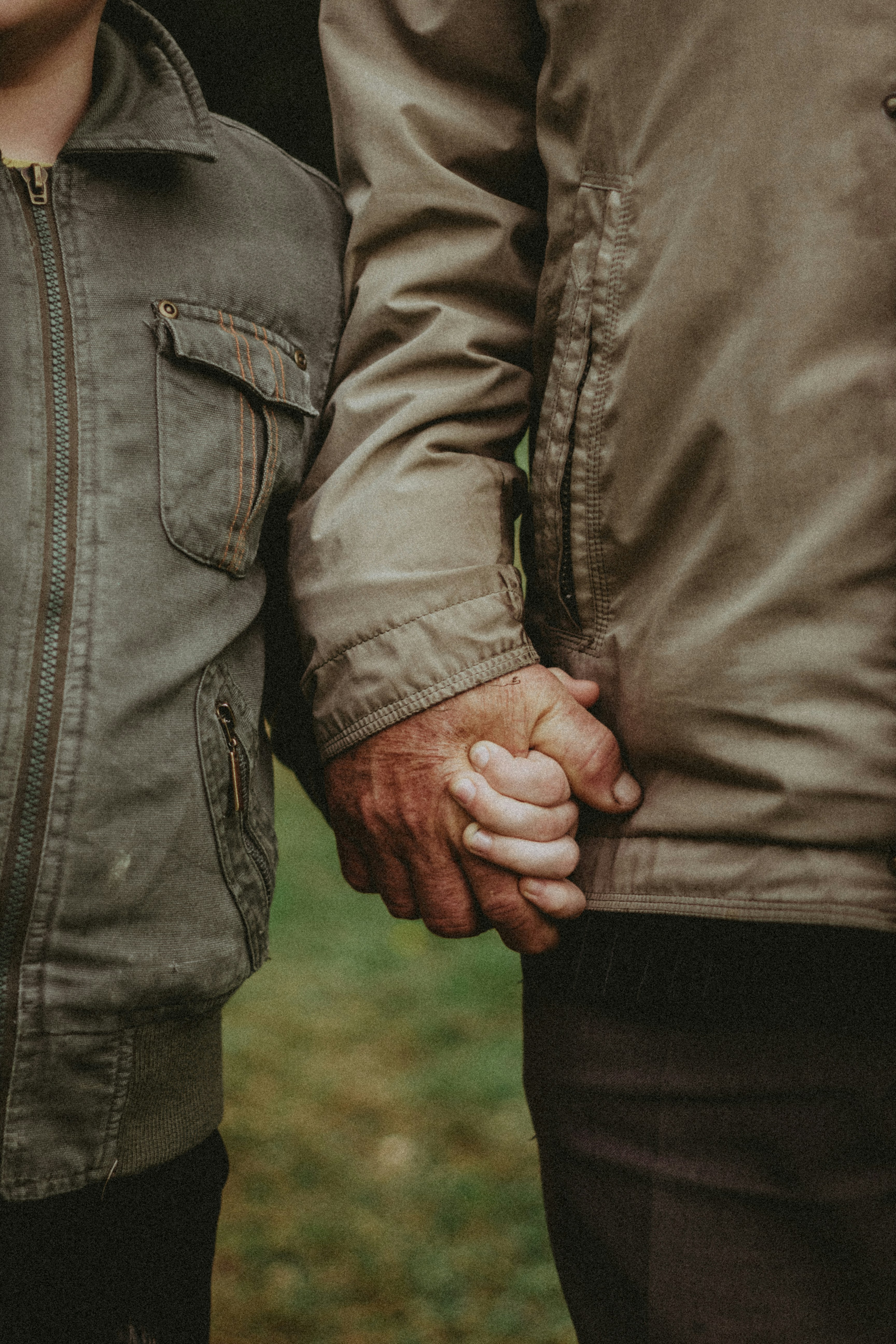 Adult and child holding hands outdoors in jackets