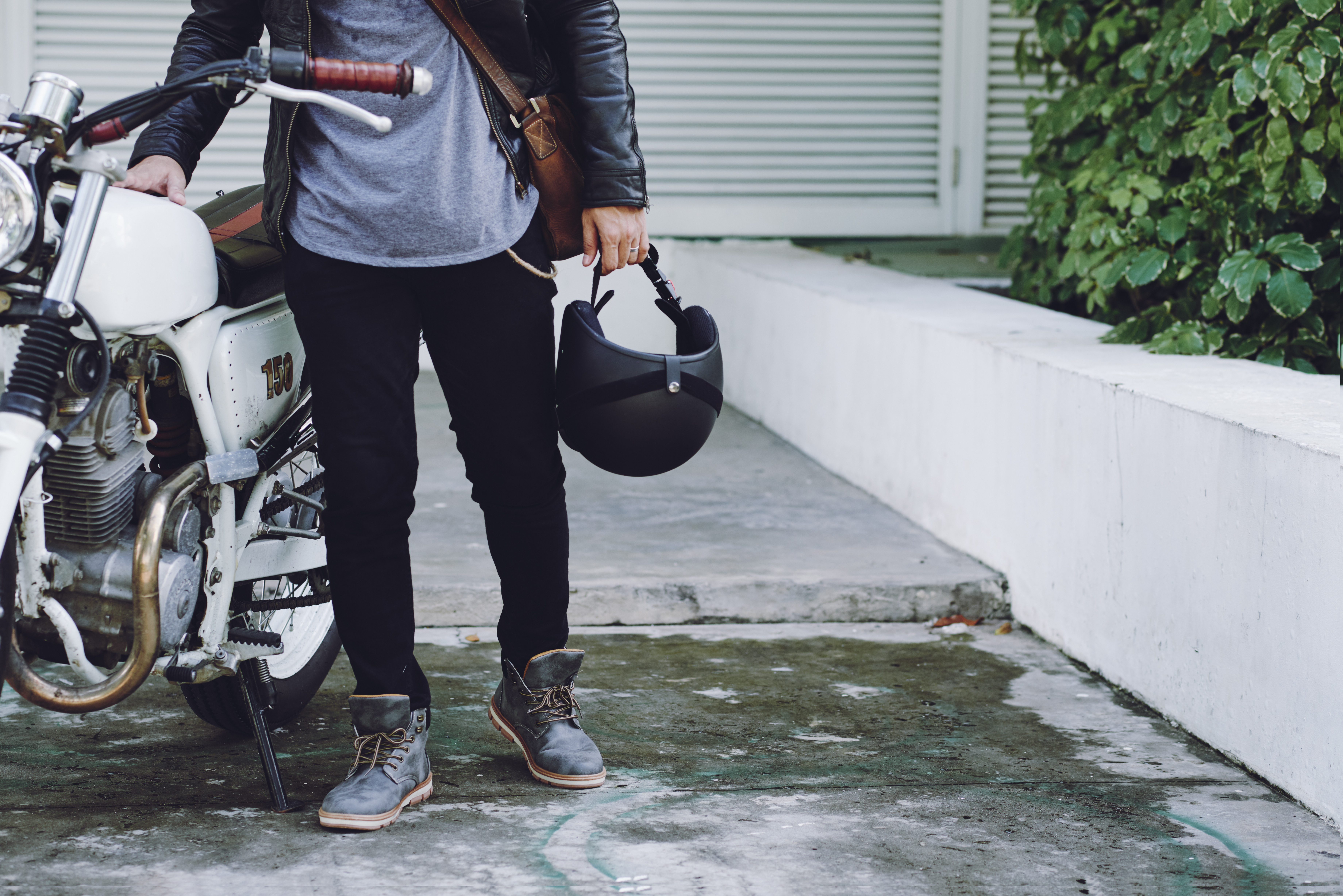 Person standing next to a motorcycle holding a helmet