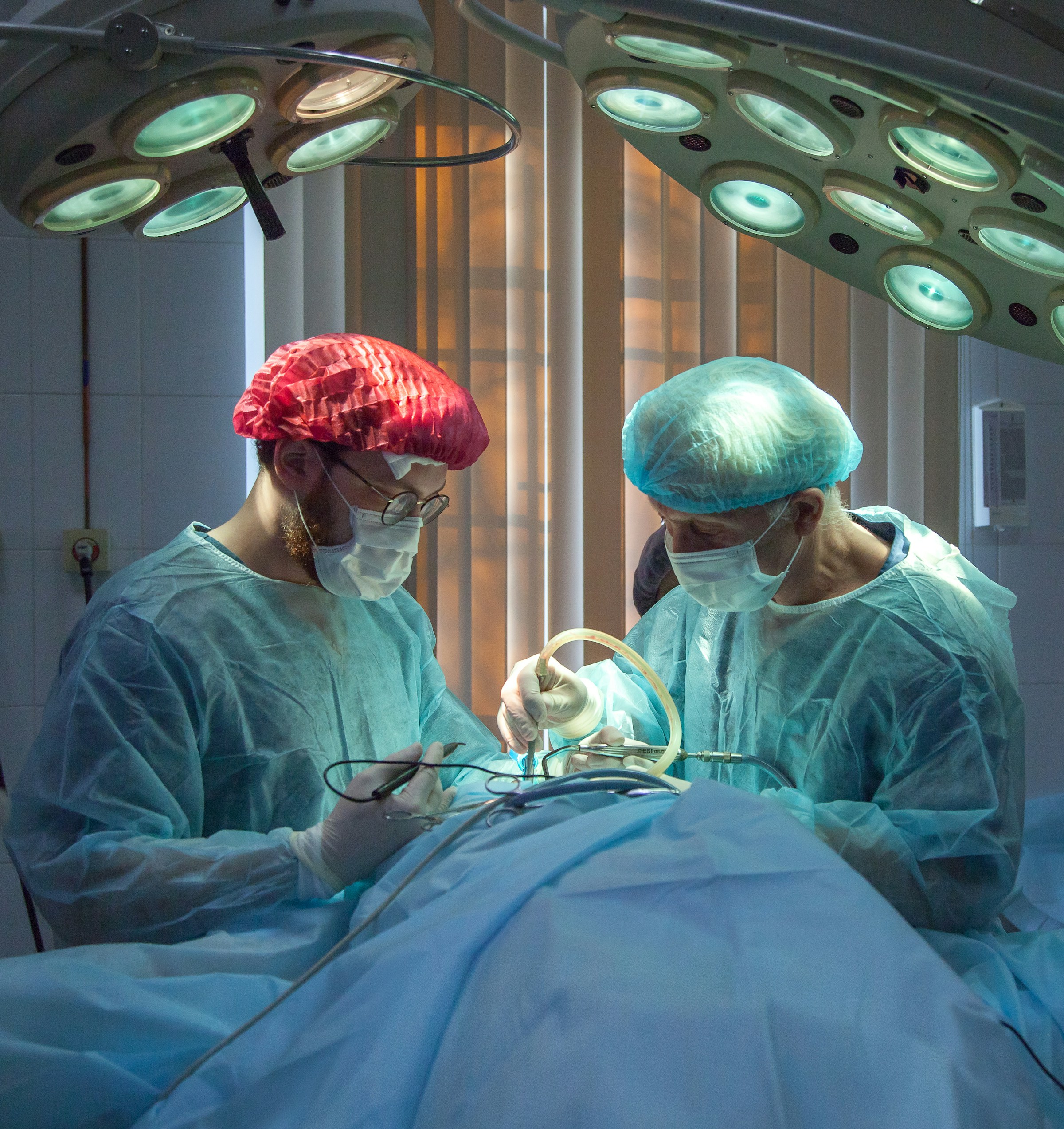 Two surgeons performing surgery under bright operating room lights