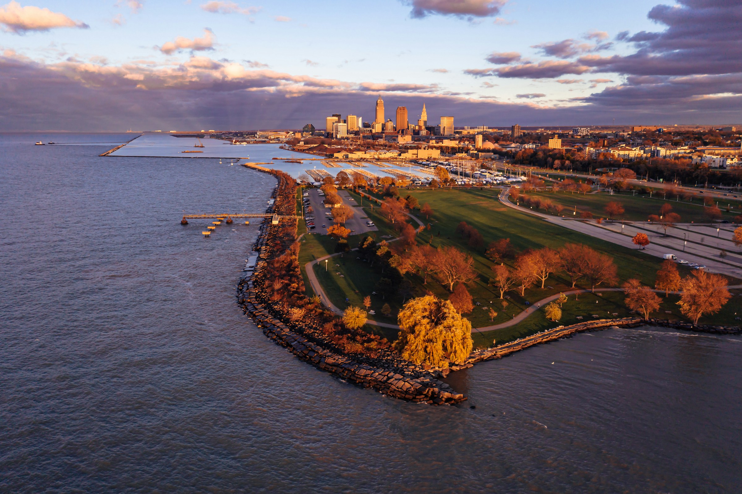 Aerial view of a city skyline with a park and waterfront at sunset
