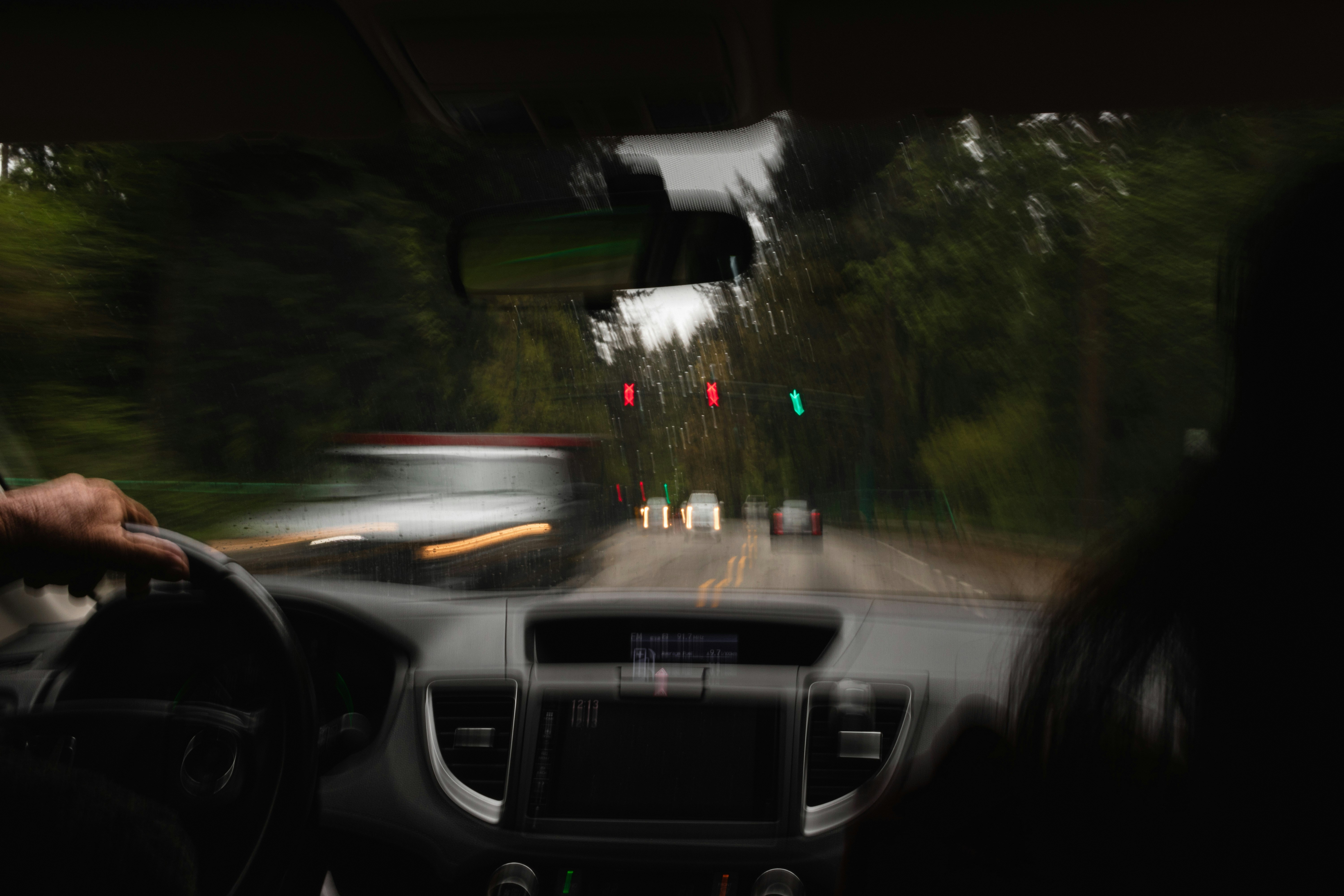 Blurred view from inside a car driving towards a traffic light on a rainy day