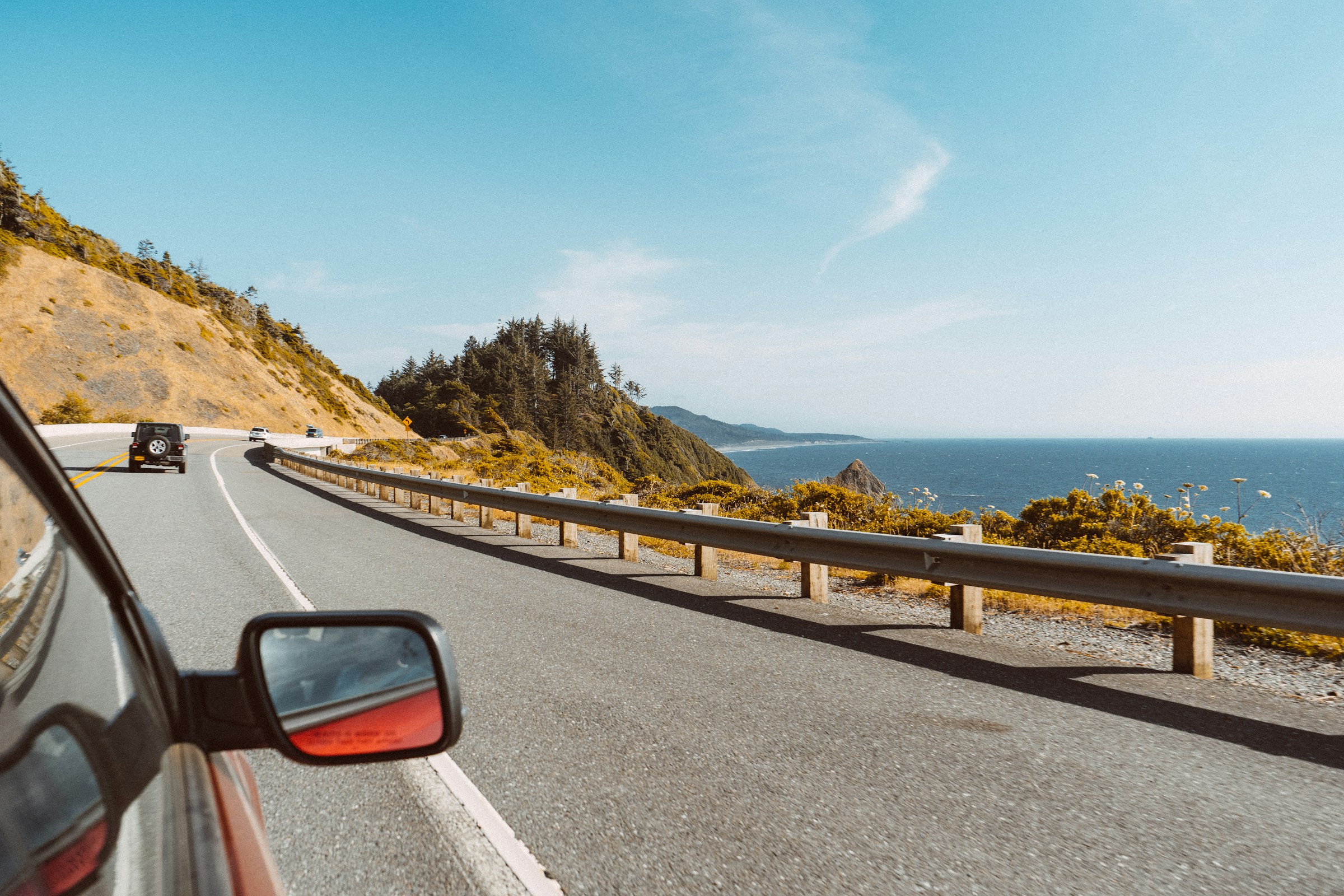 Cars driving on a coastal highway with ocean view and clear sky