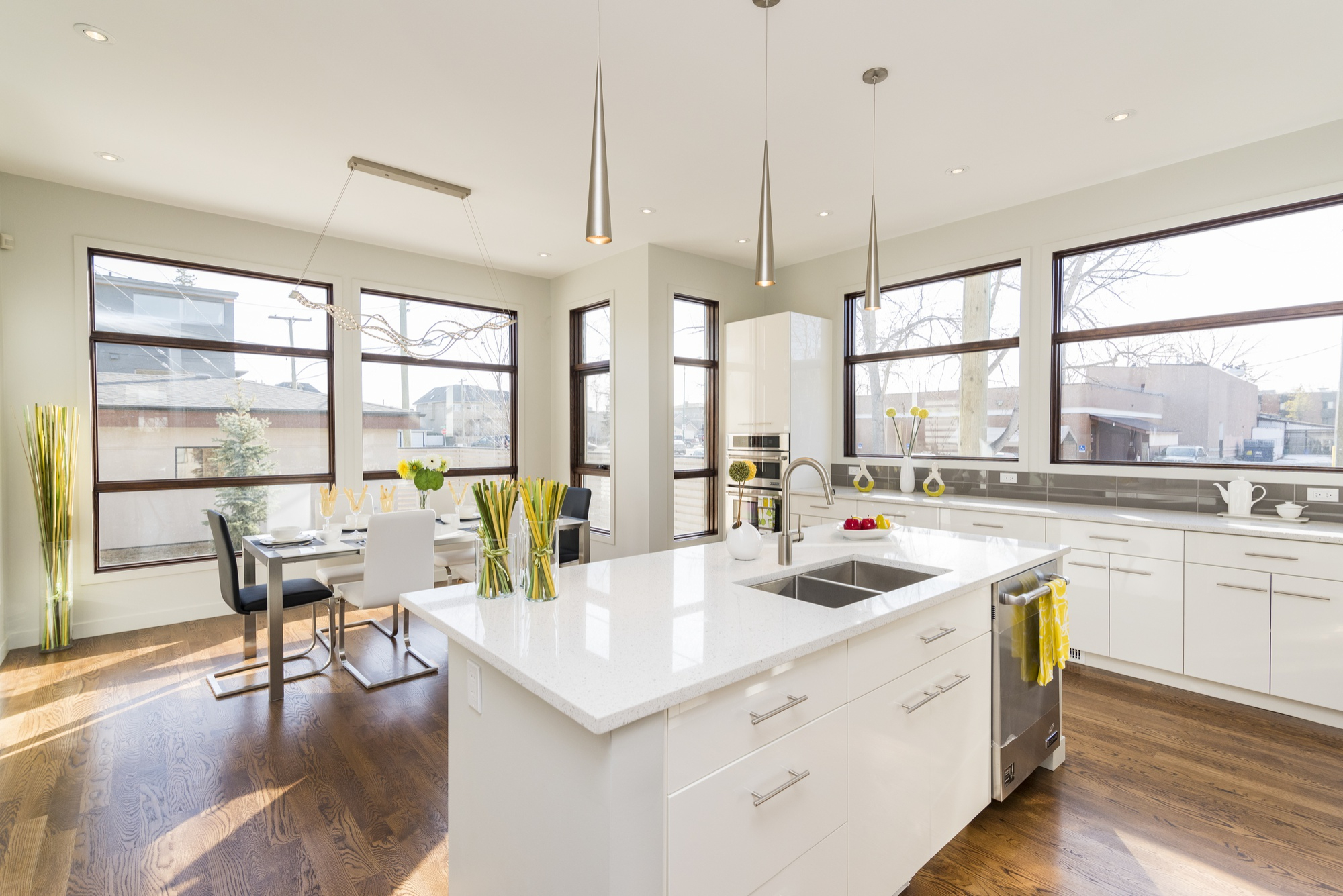 Modern kitchen with white cabinetry, large island, and dining area with large windows.