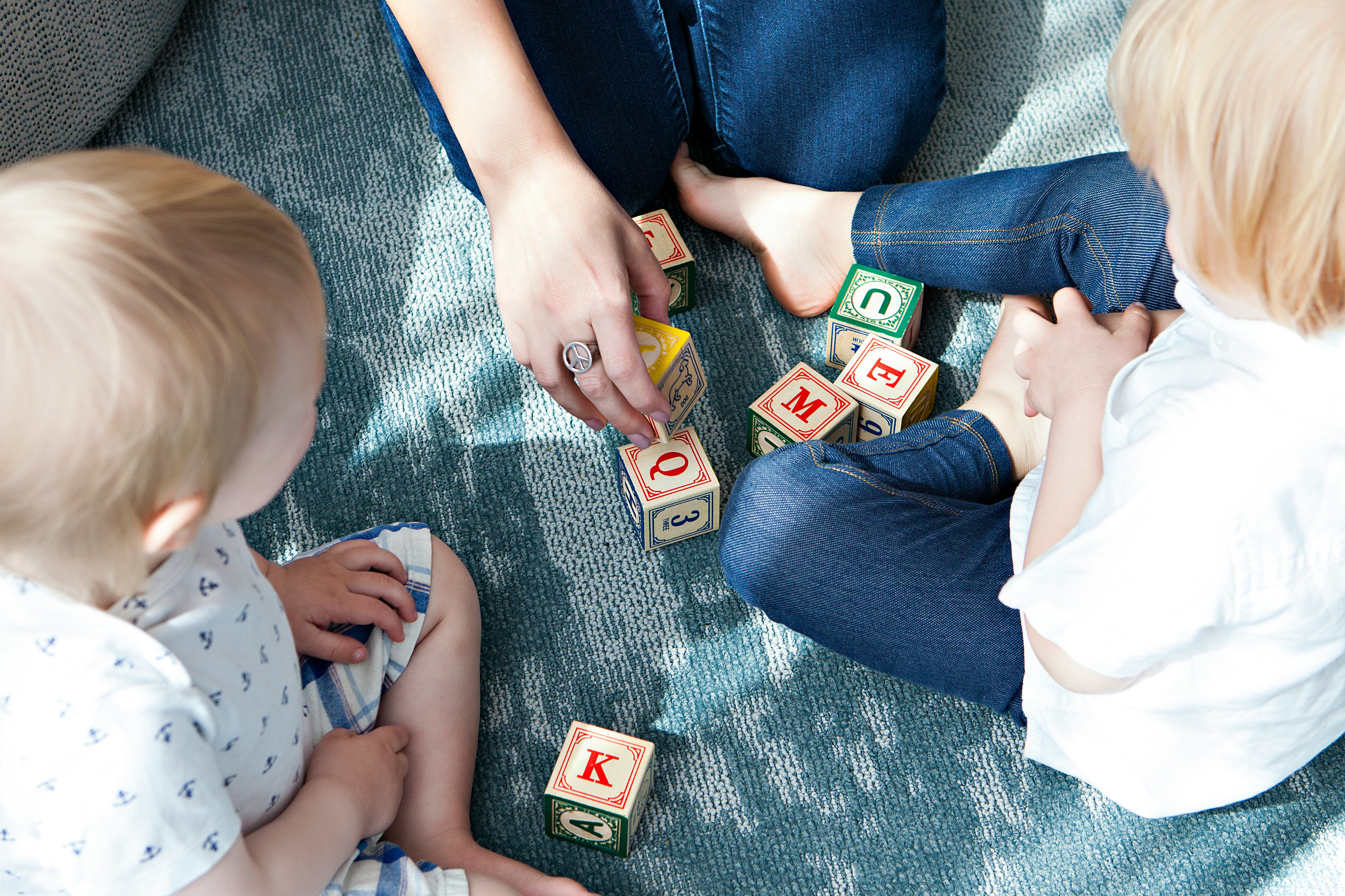 Children playing with alphabet blocks on a blue carpet