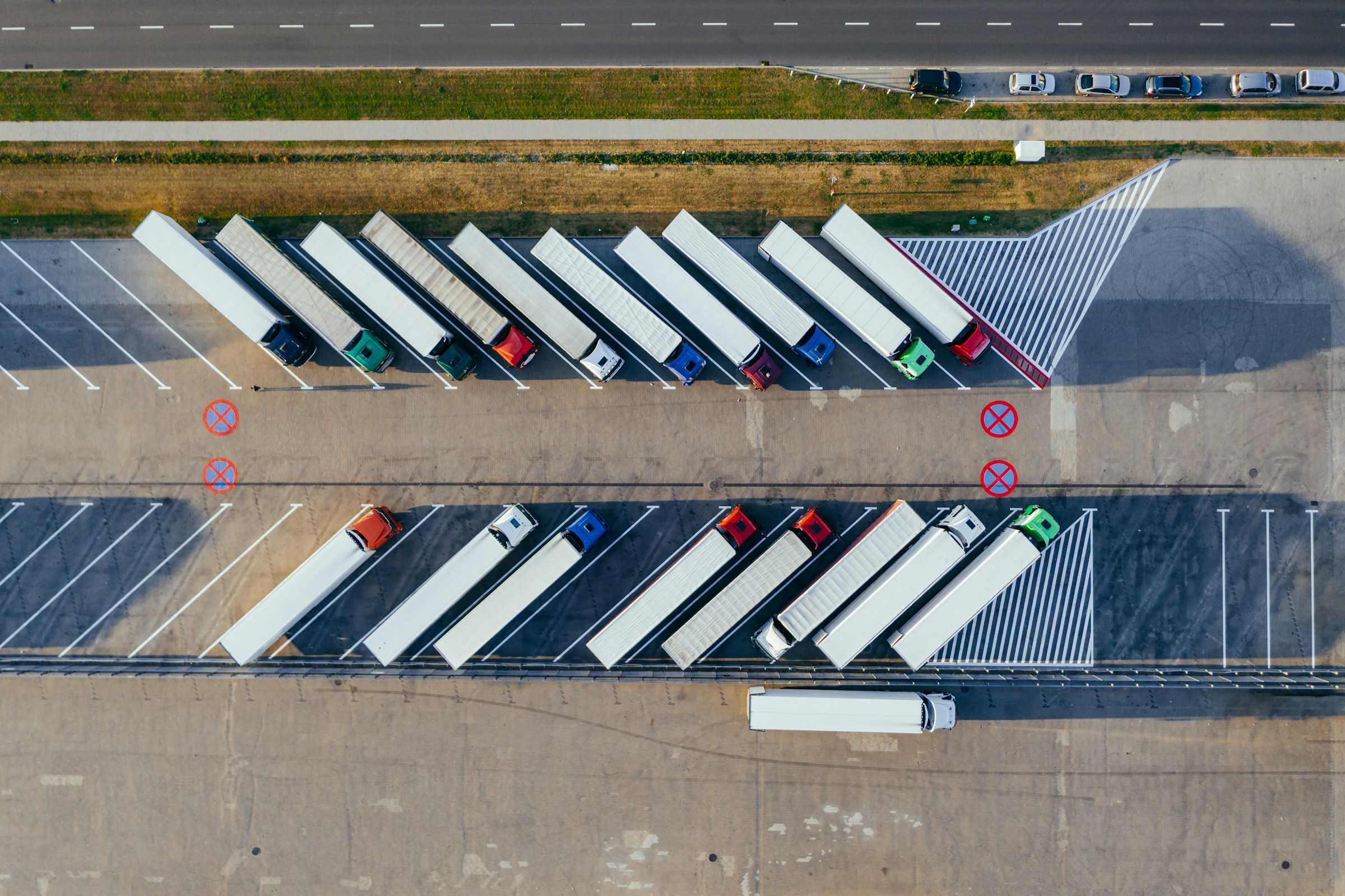 Aerial view of multiple trucks parked in a lot with marked parking spaces