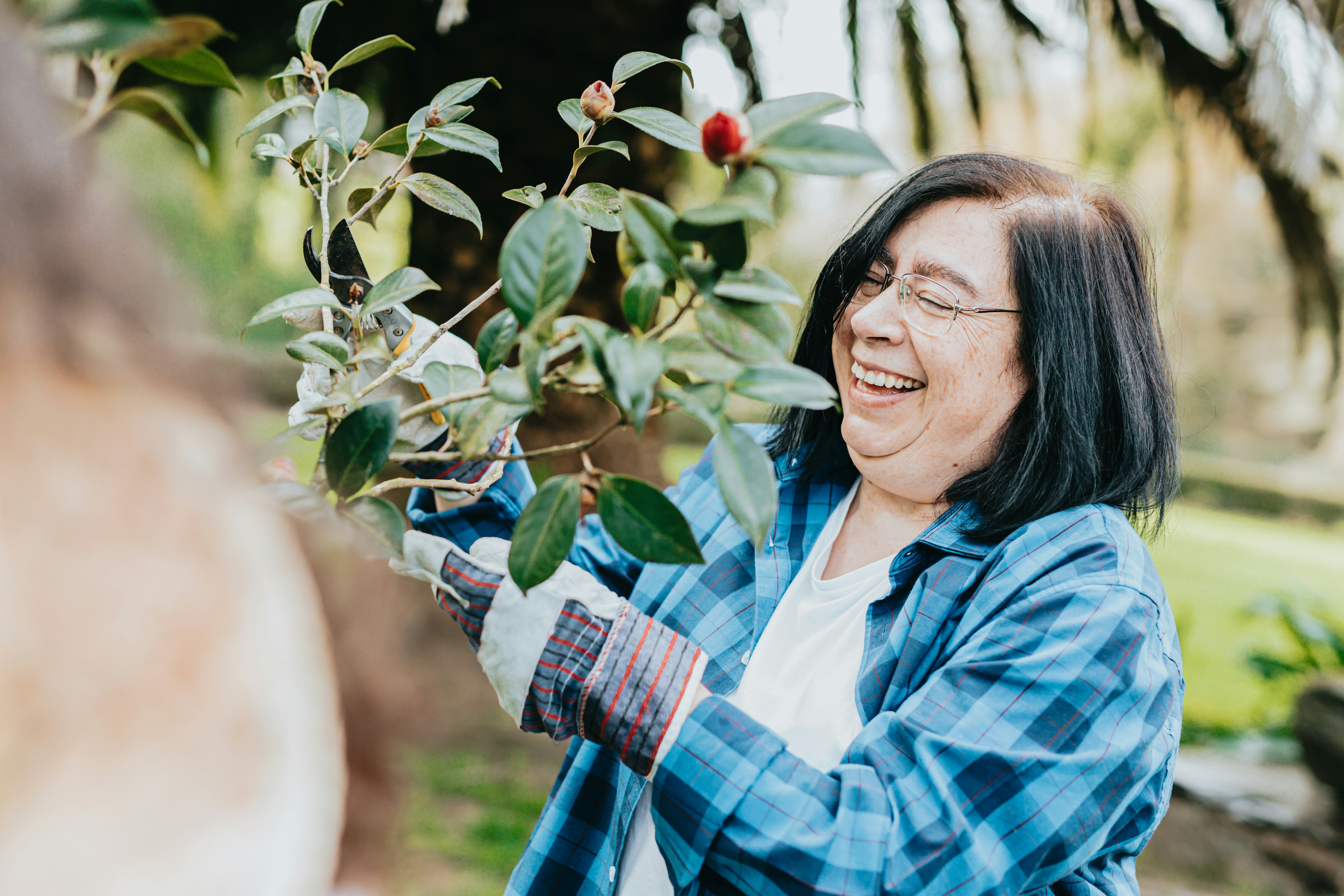 Person smiling while tending to a plant in a garden