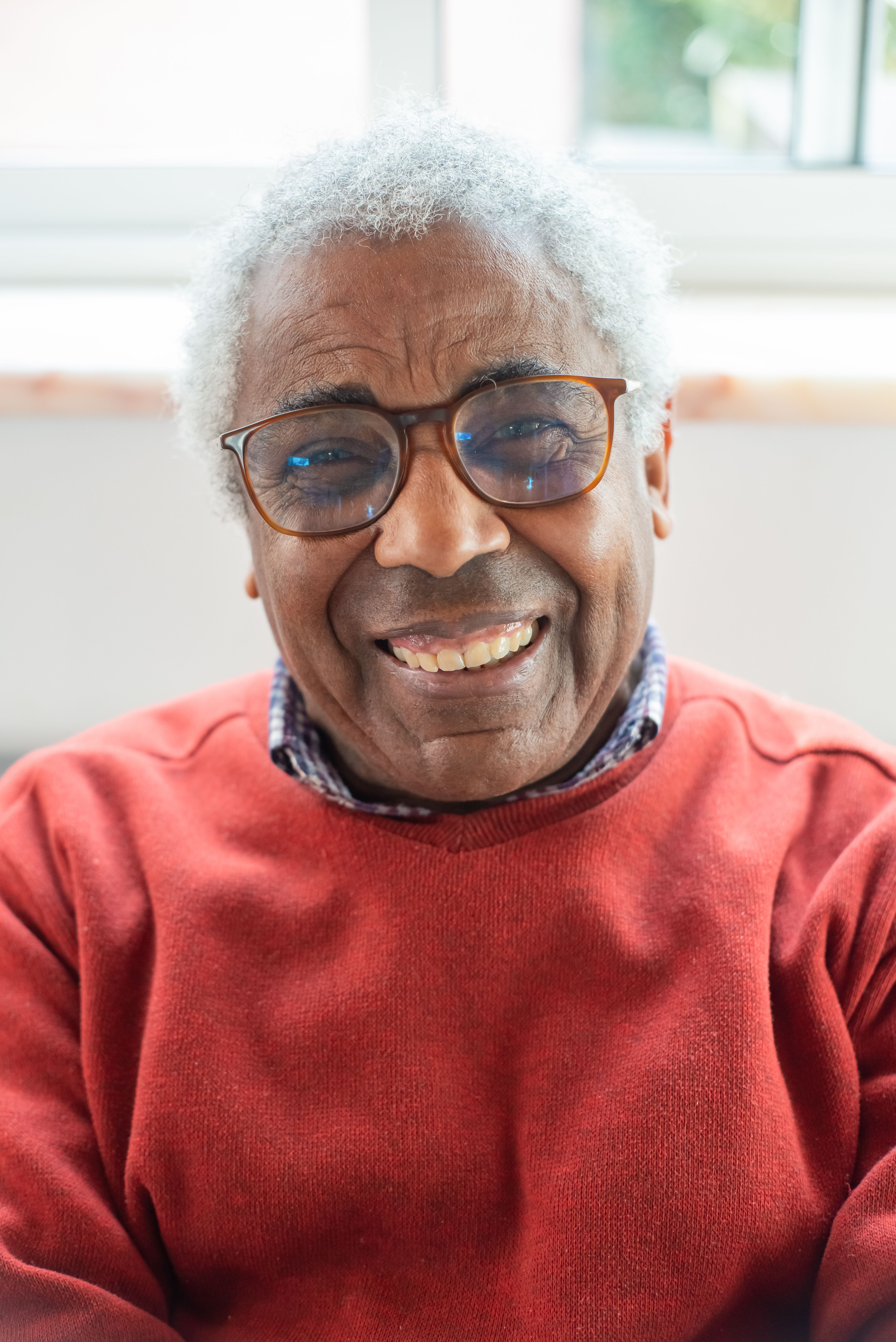 Elderly man with glasses smiling warmly at the camera