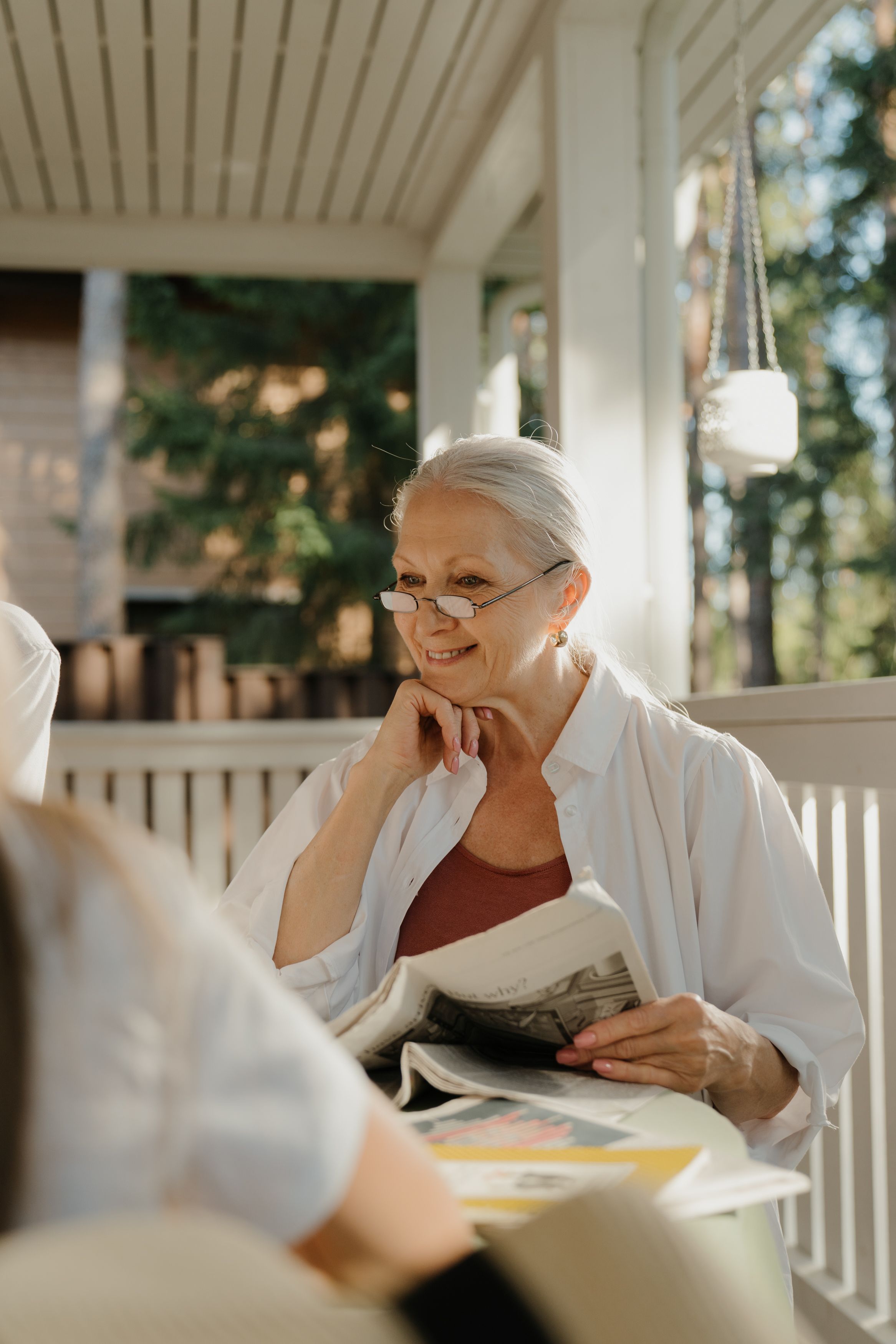 Elderly woman reading a newspaper on a porch