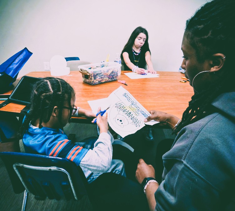 A group of children are sitting on the ground playing with clay.