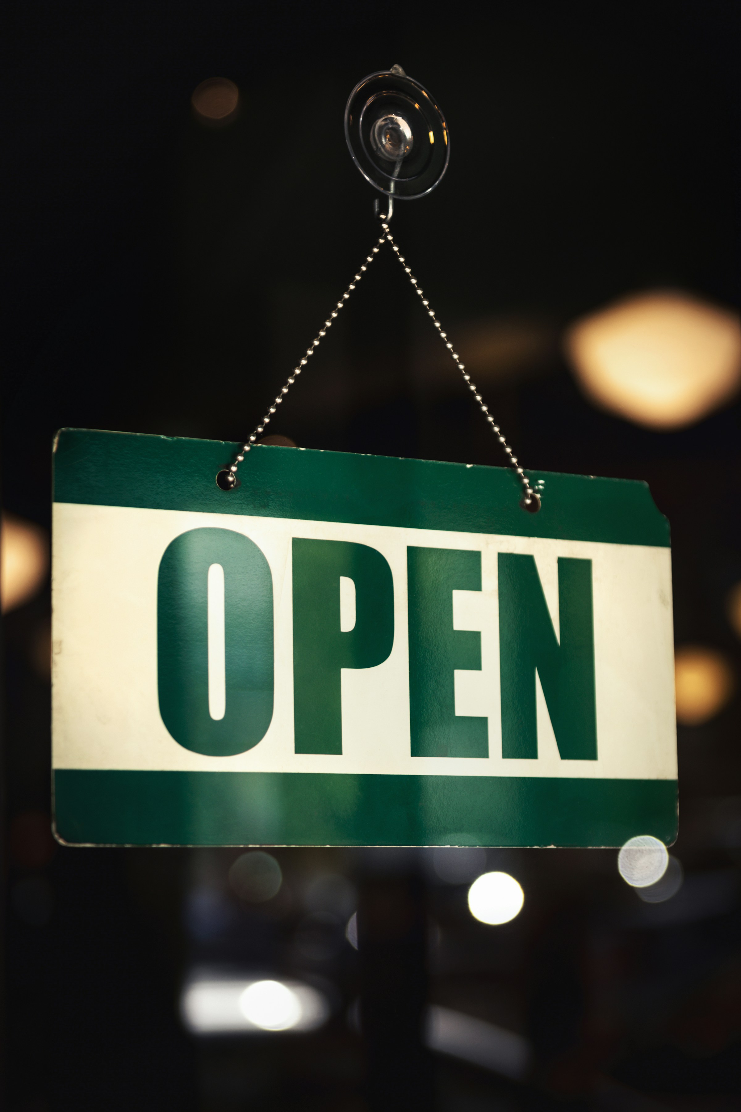 Green and white open sign hanging in a store window