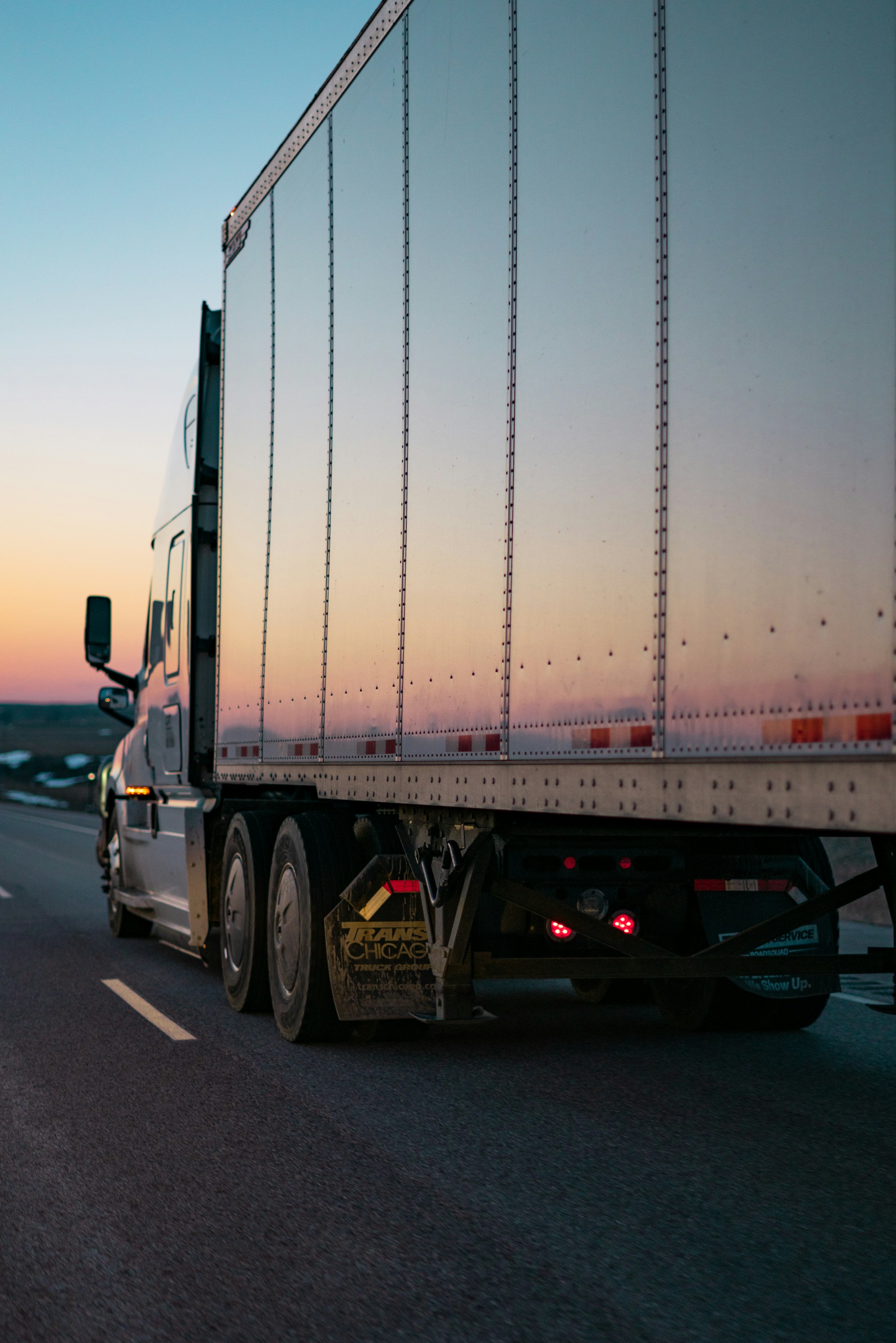 Semi-truck driving on a highway at sunset