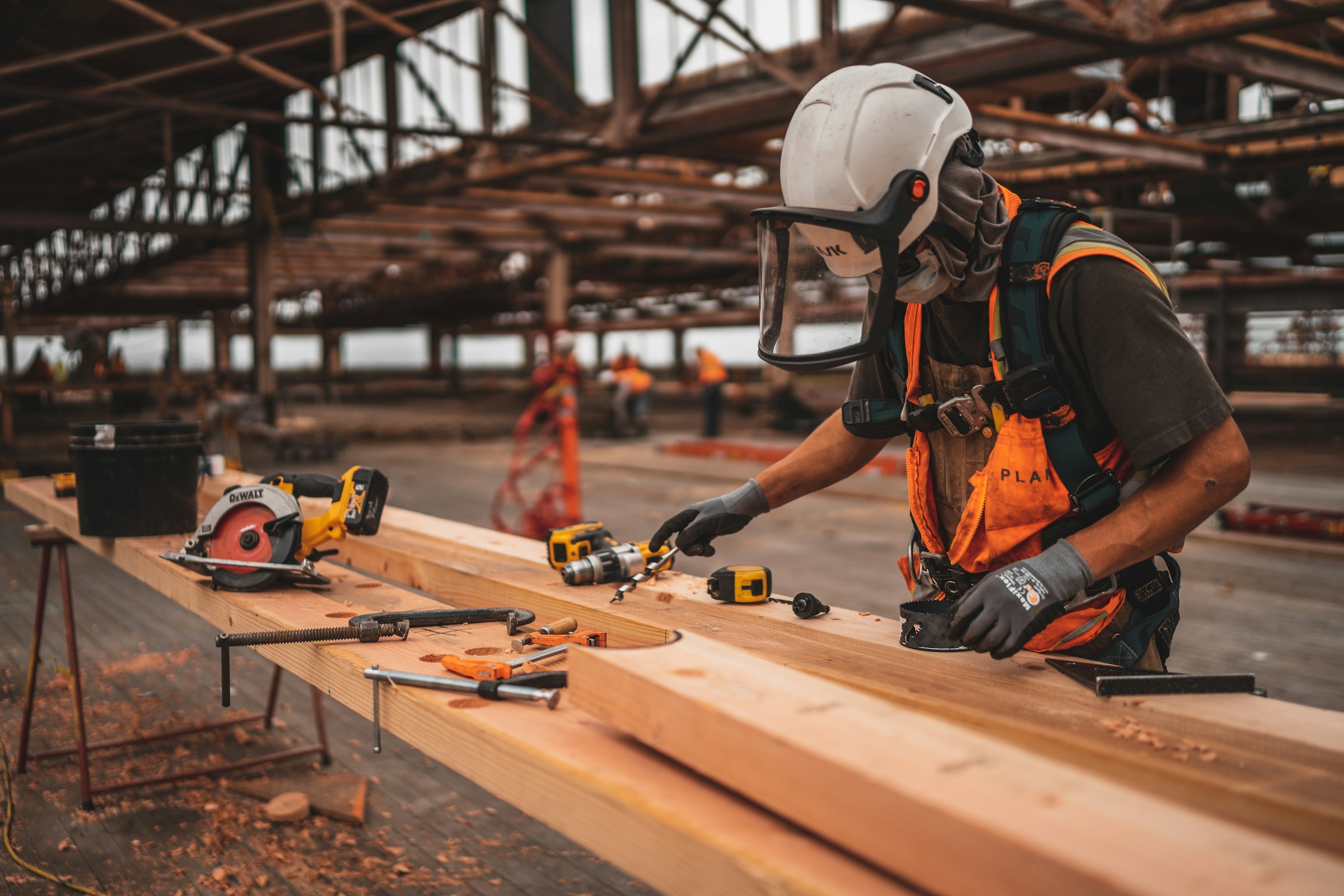 Construction worker using tools on wooden beams at a construction site