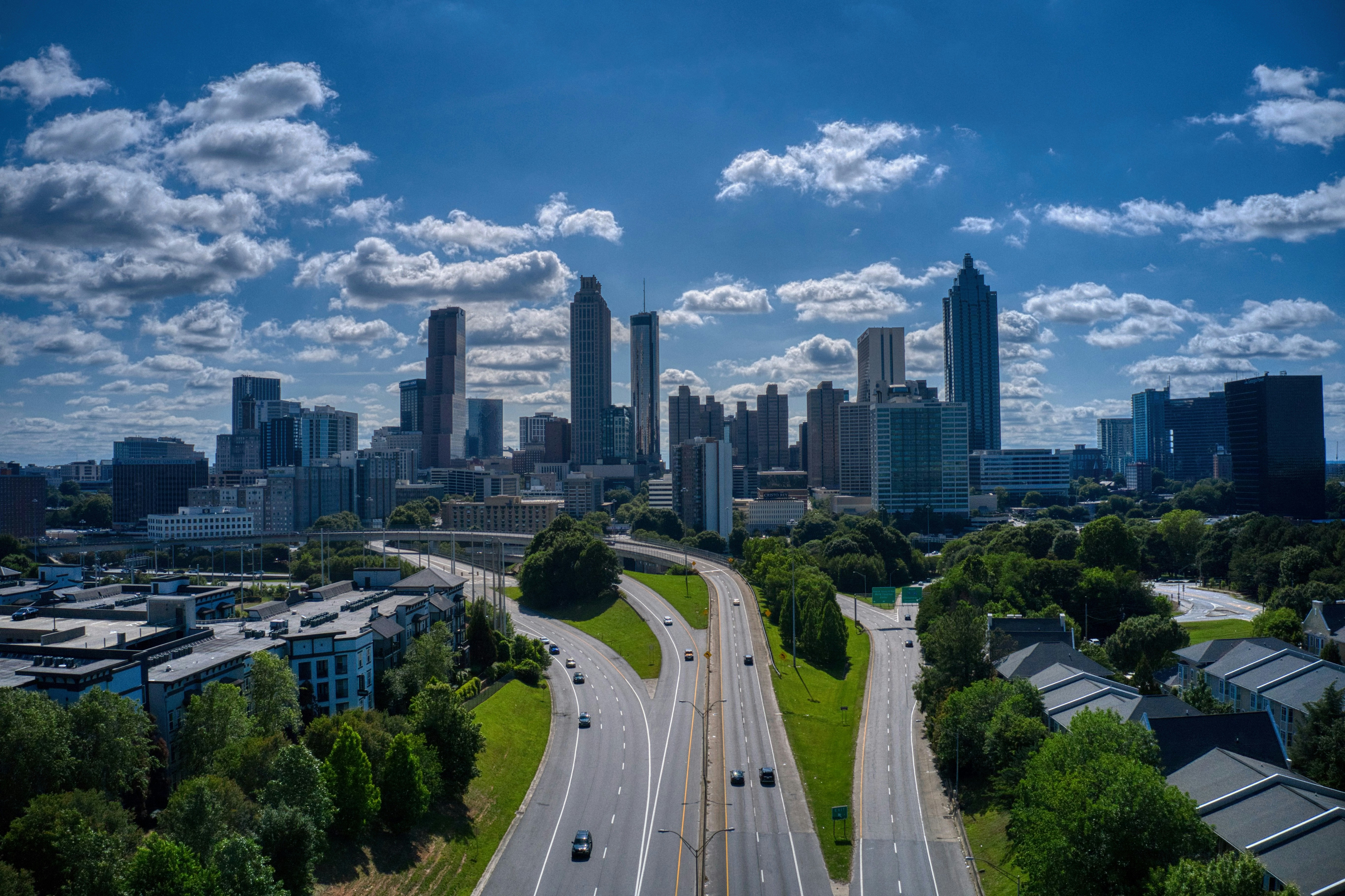 Aerial view of a city skyline with highways and buildings under a blue sky