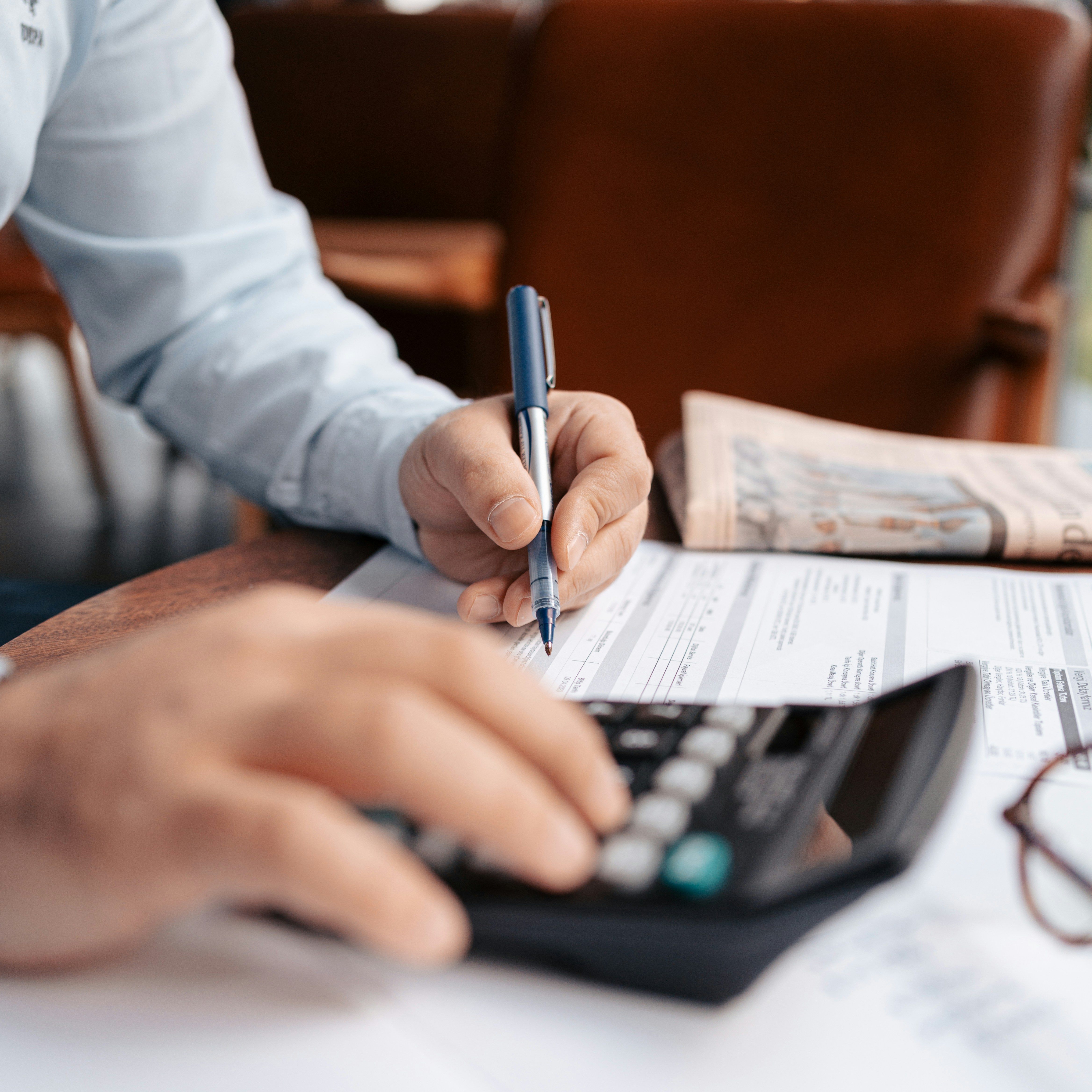 Person using a calculator and writing on financial documents