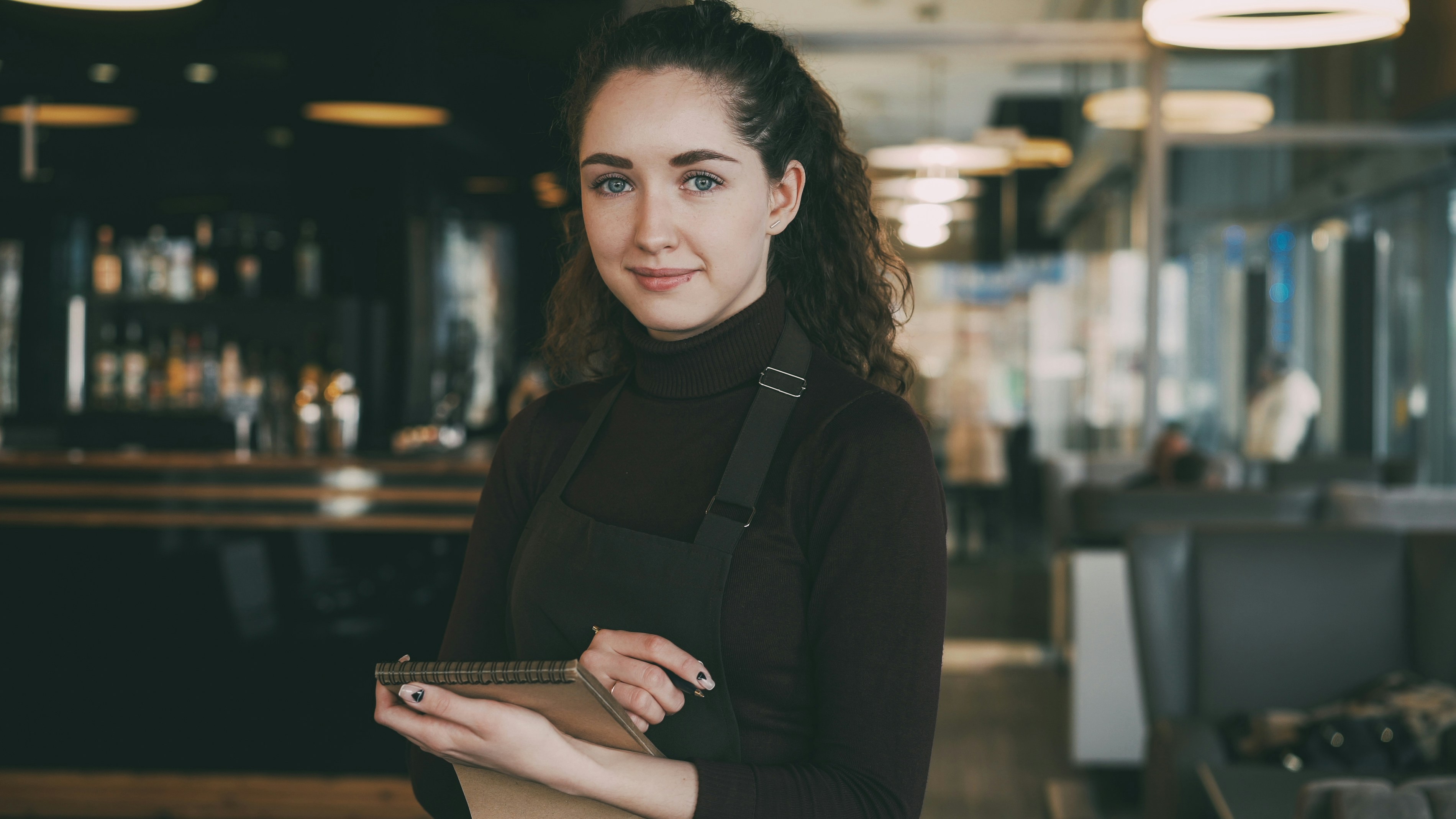 Smiling waitress holding a notepad in a modern restaurant