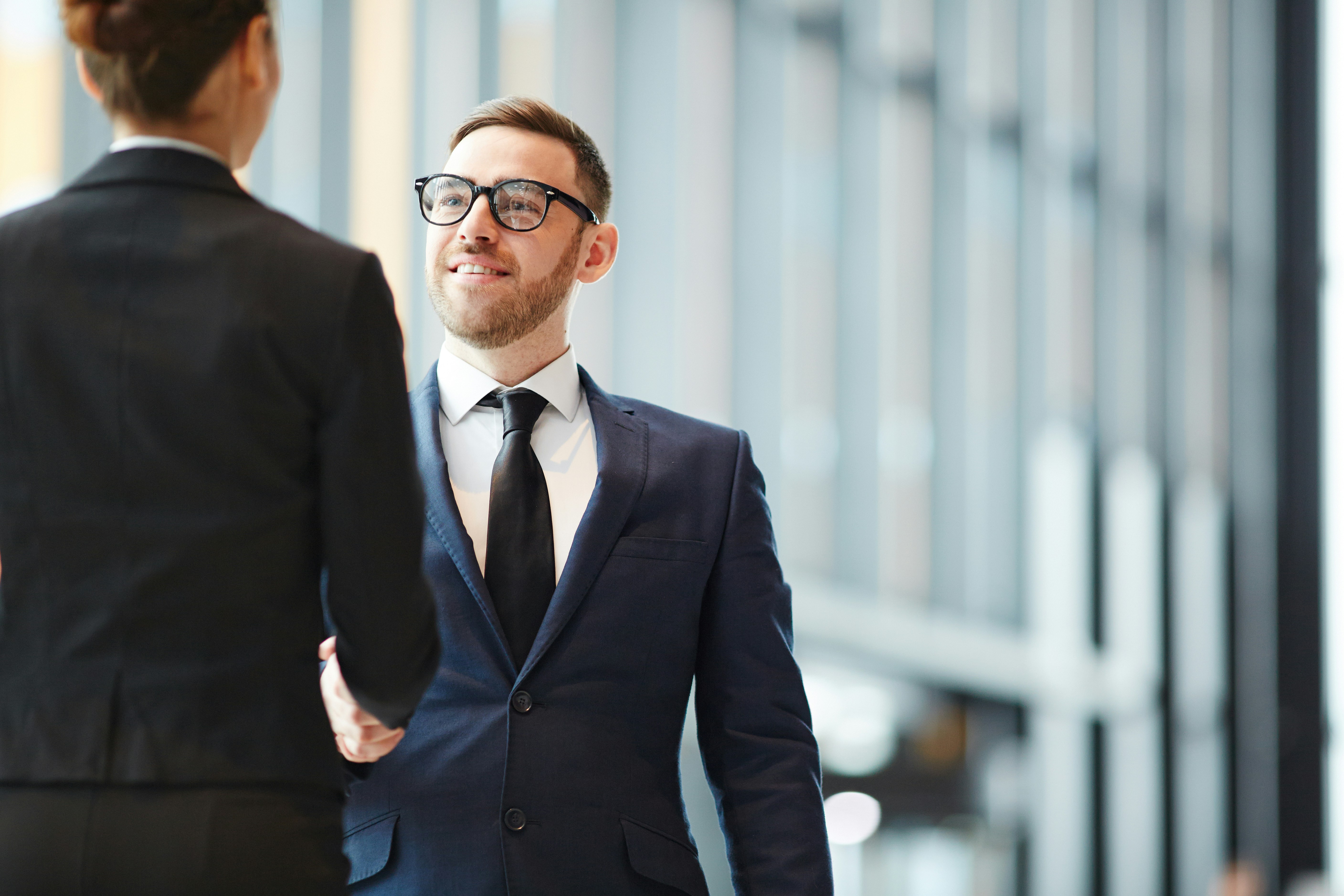 Two business professionals shaking hands in a modern office building