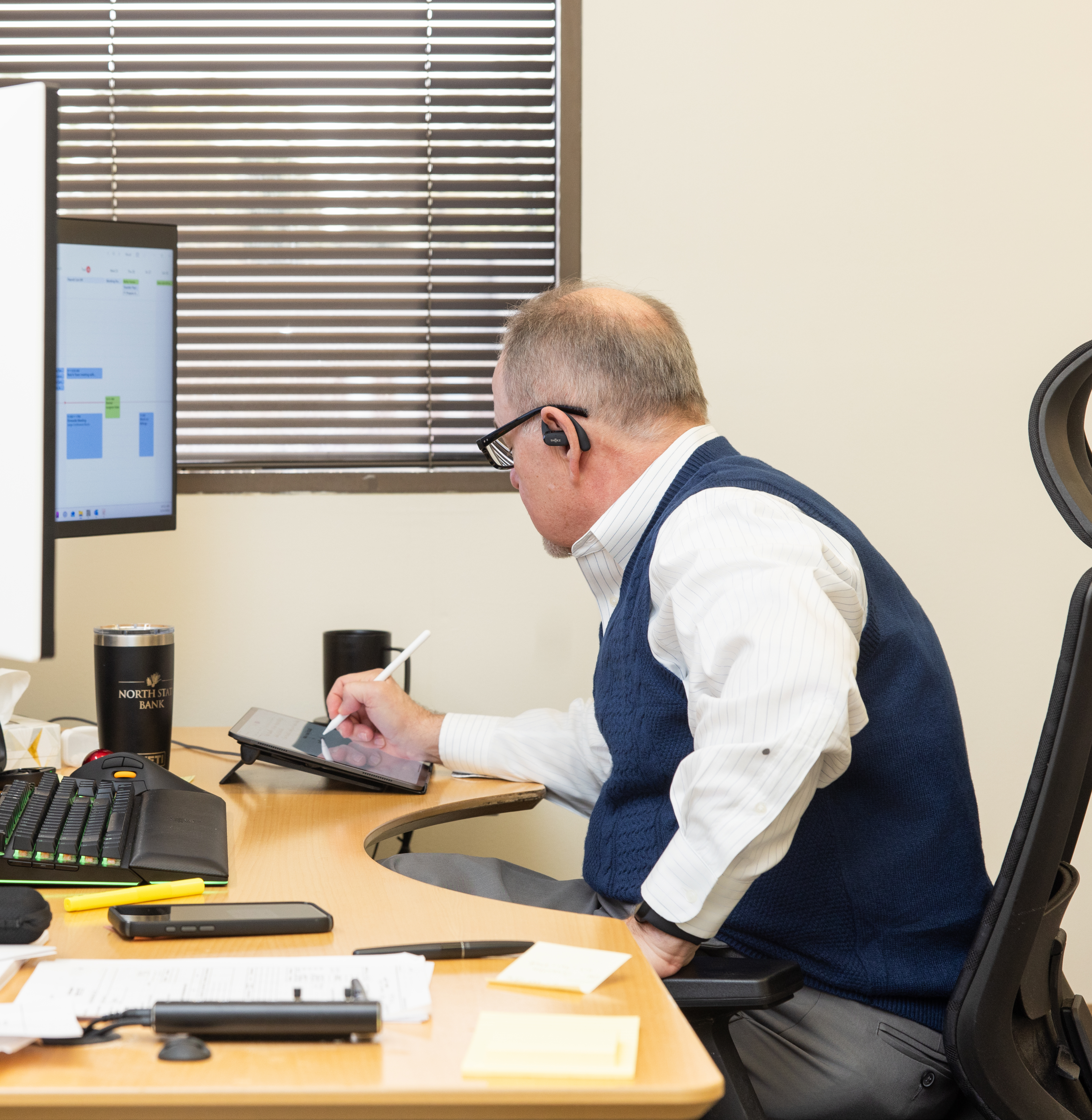 Man working at a desk with a tablet and computer monitors.