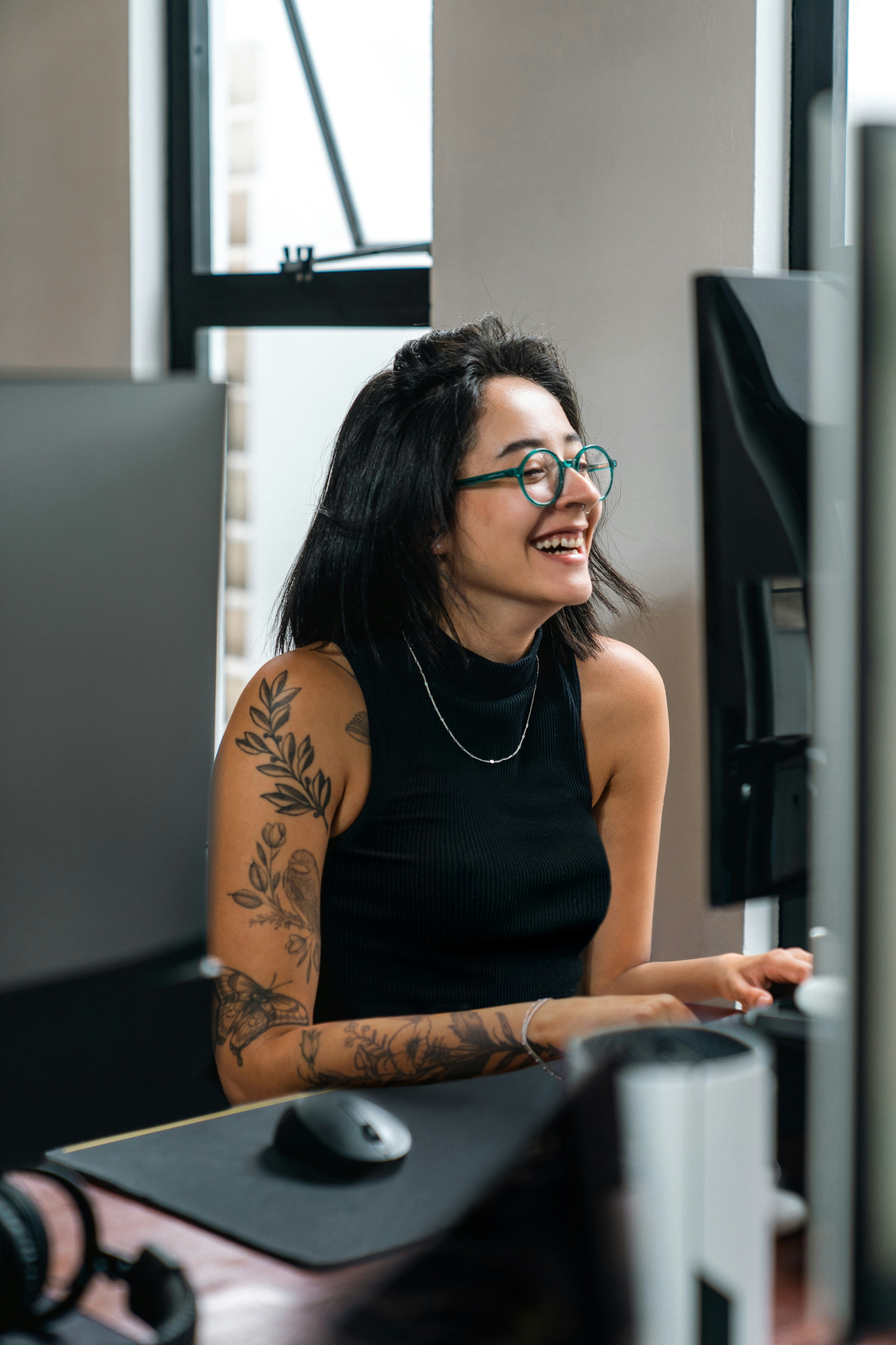 Smiling woman with glasses working at a computer in an office