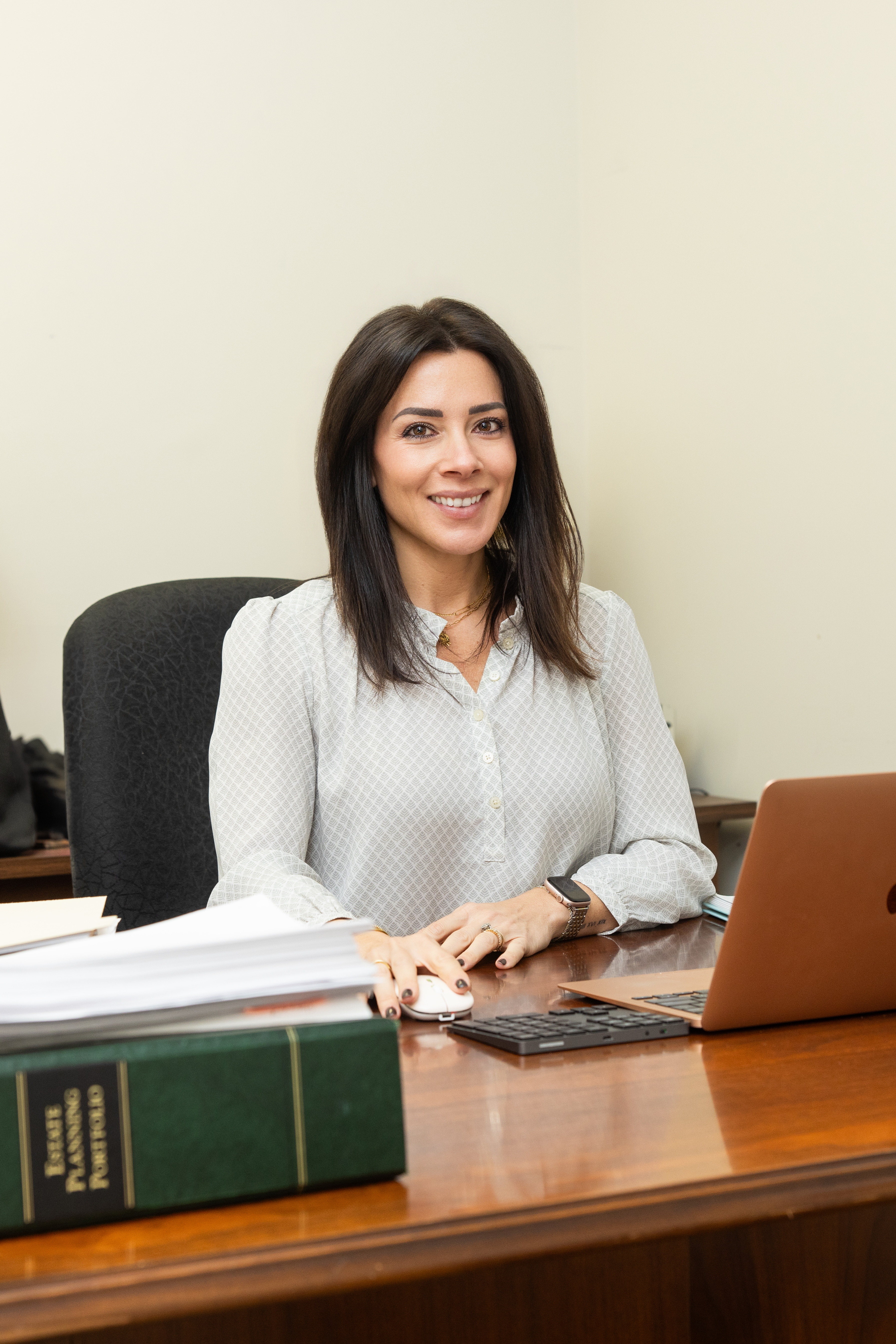 Professional woman sitting at a desk with a laptop and legal books.