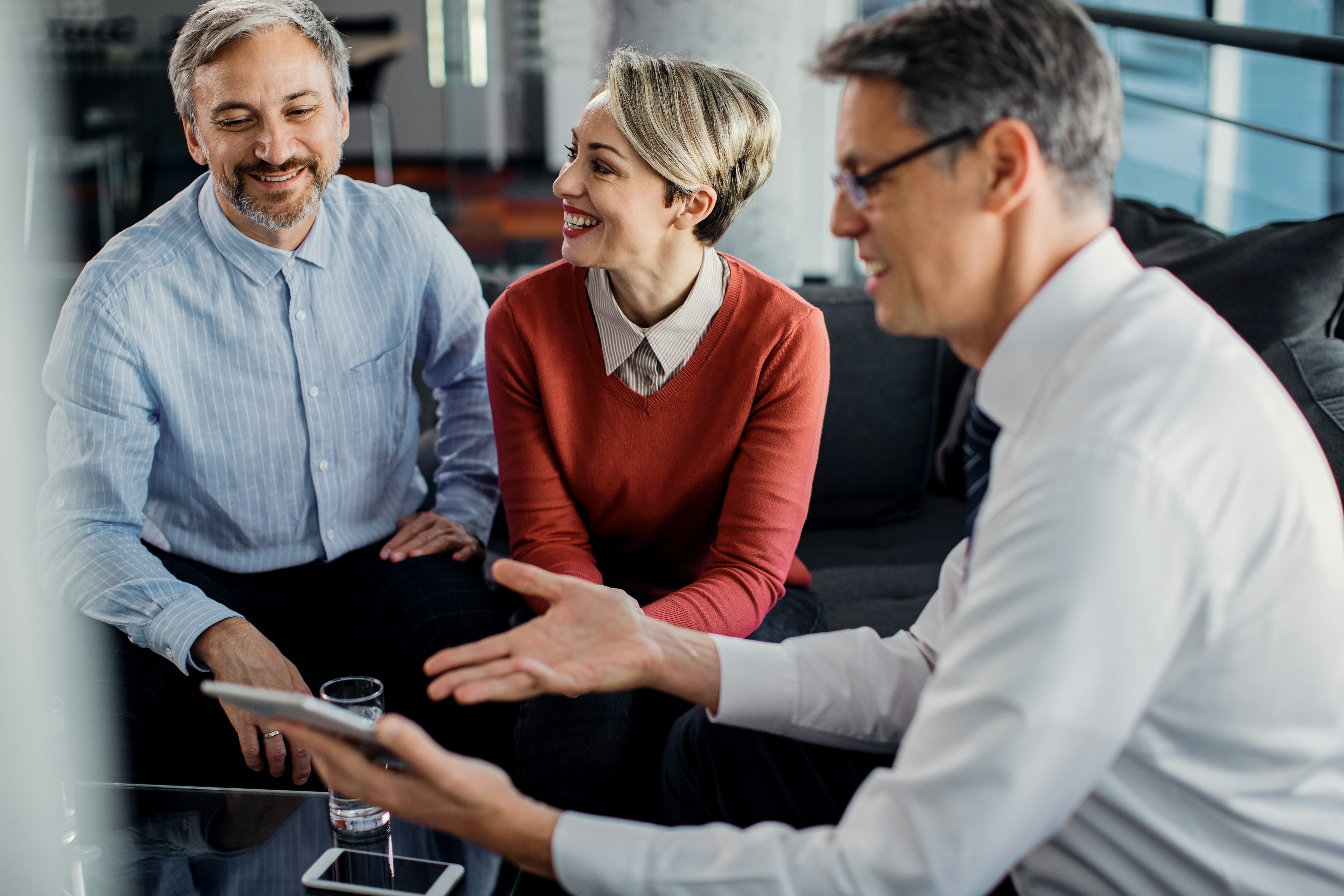 Business professional discussing information on a tablet with a smiling couple.