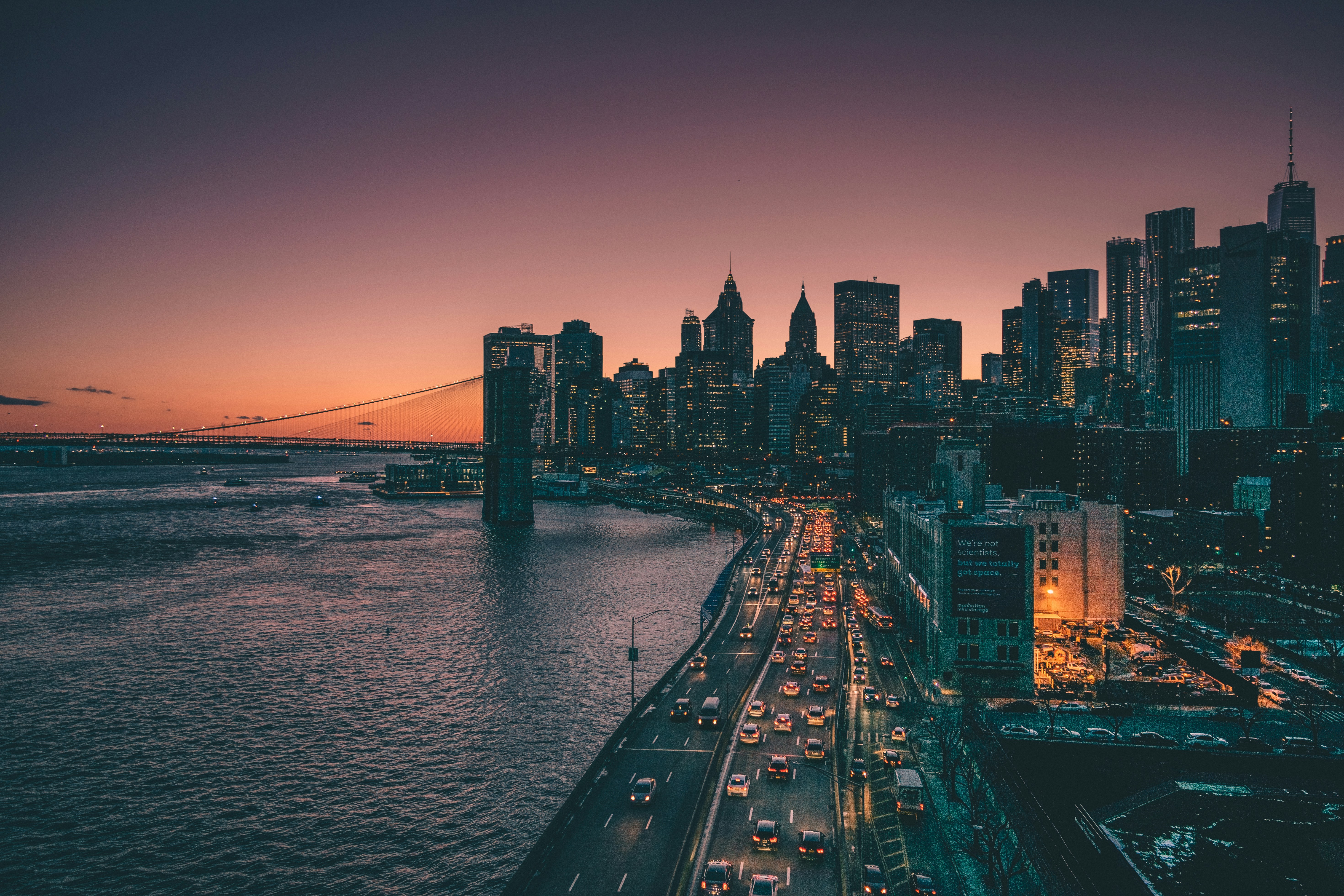 City skyline at dusk with illuminated buildings and a busy highway