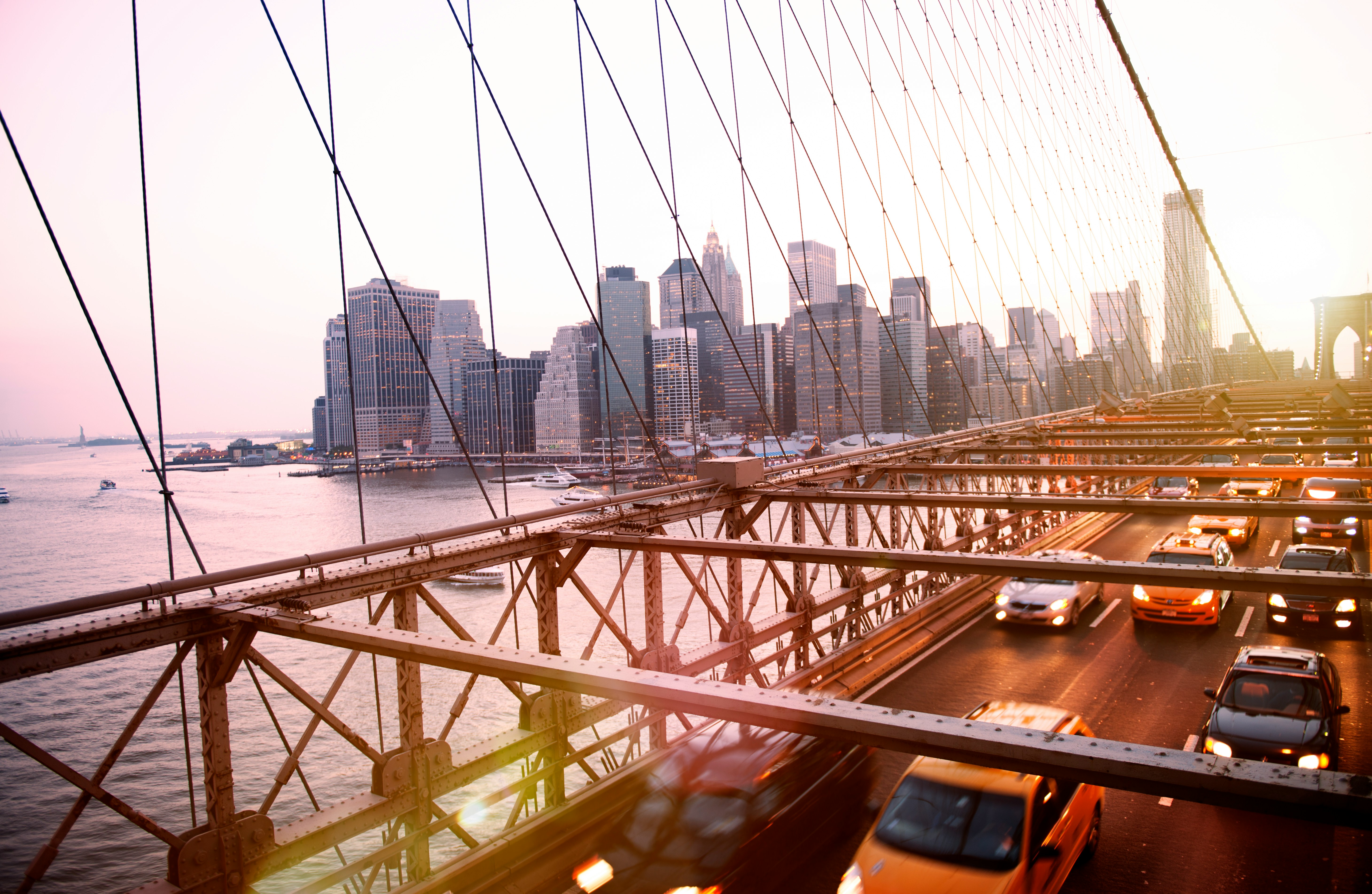 Traffic on a bridge with a city skyline in the background at sunset
