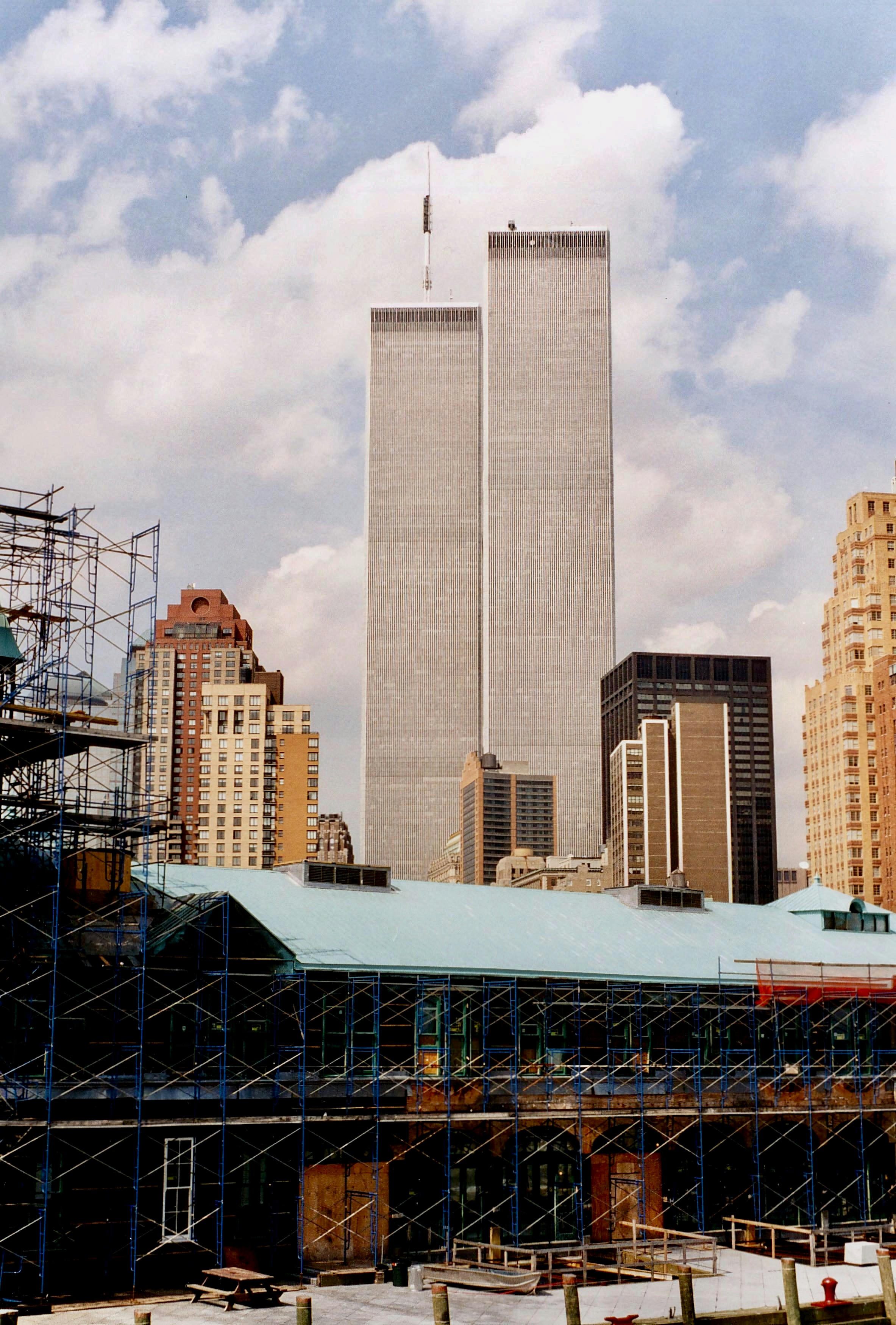View of two tall skyscrapers with scaffolding and other buildings in the foreground