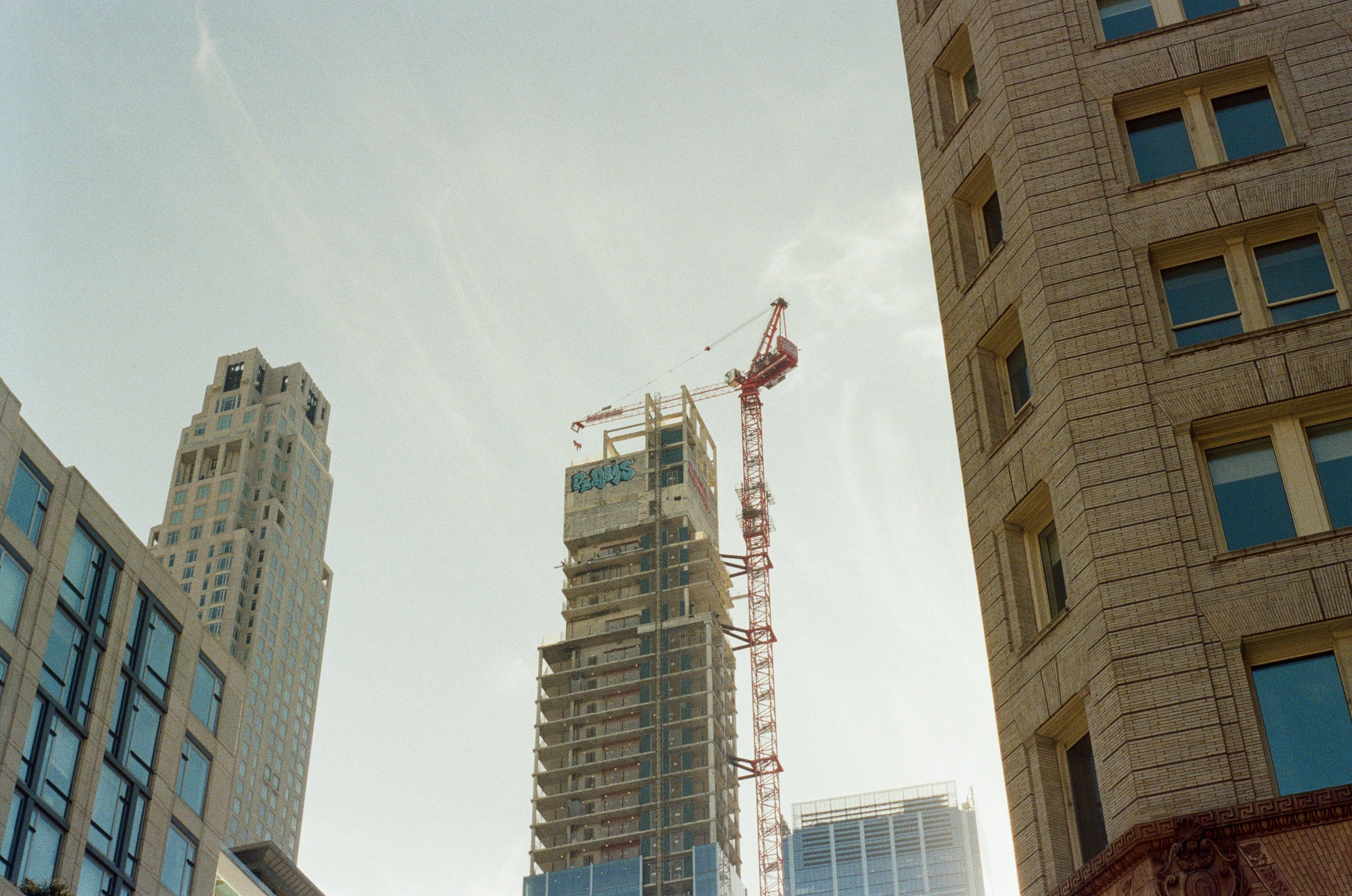 High-rise buildings with a construction crane against a clear sky