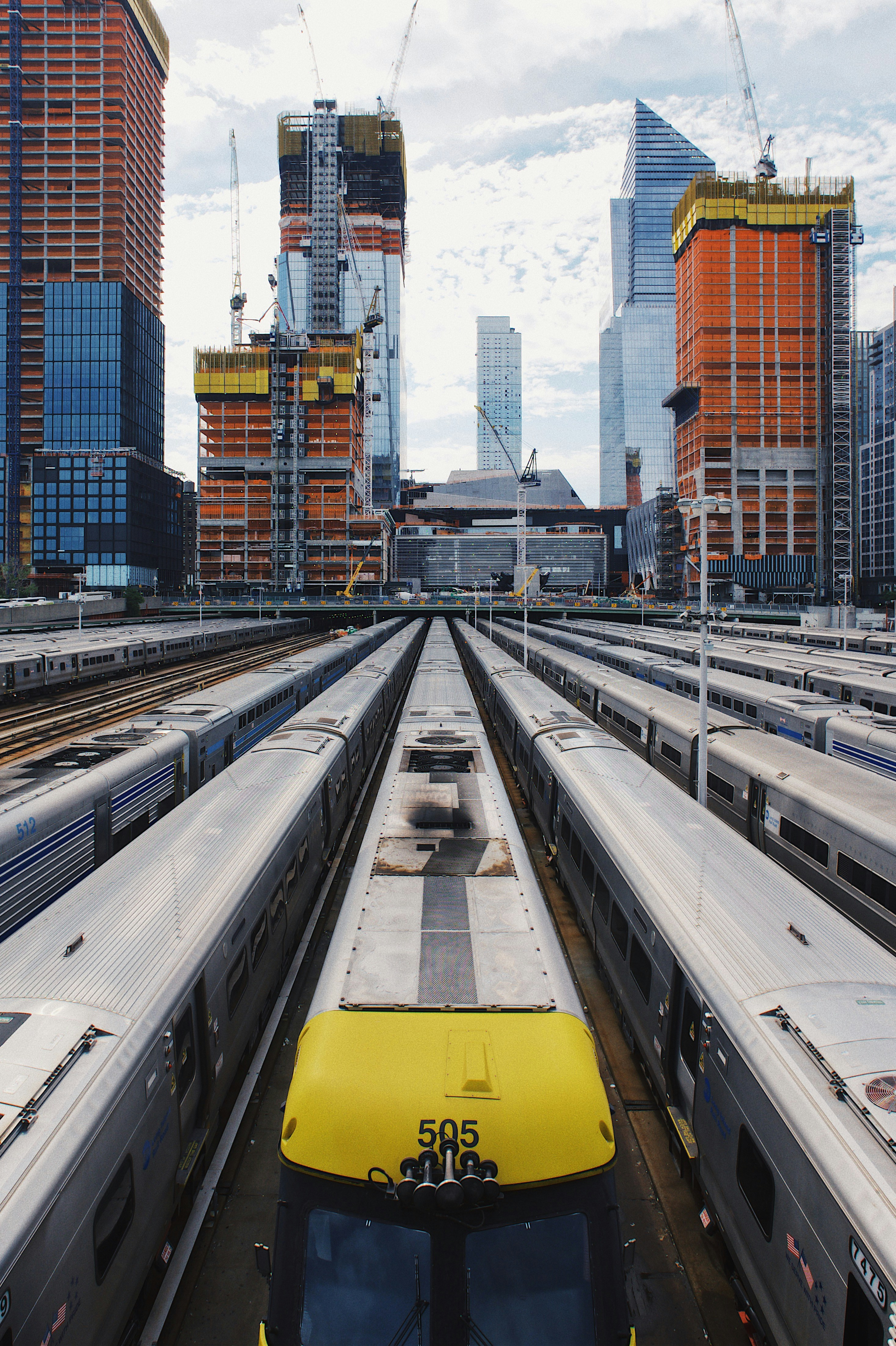 View of multiple trains at a busy urban train yard with skyscrapers in the background
