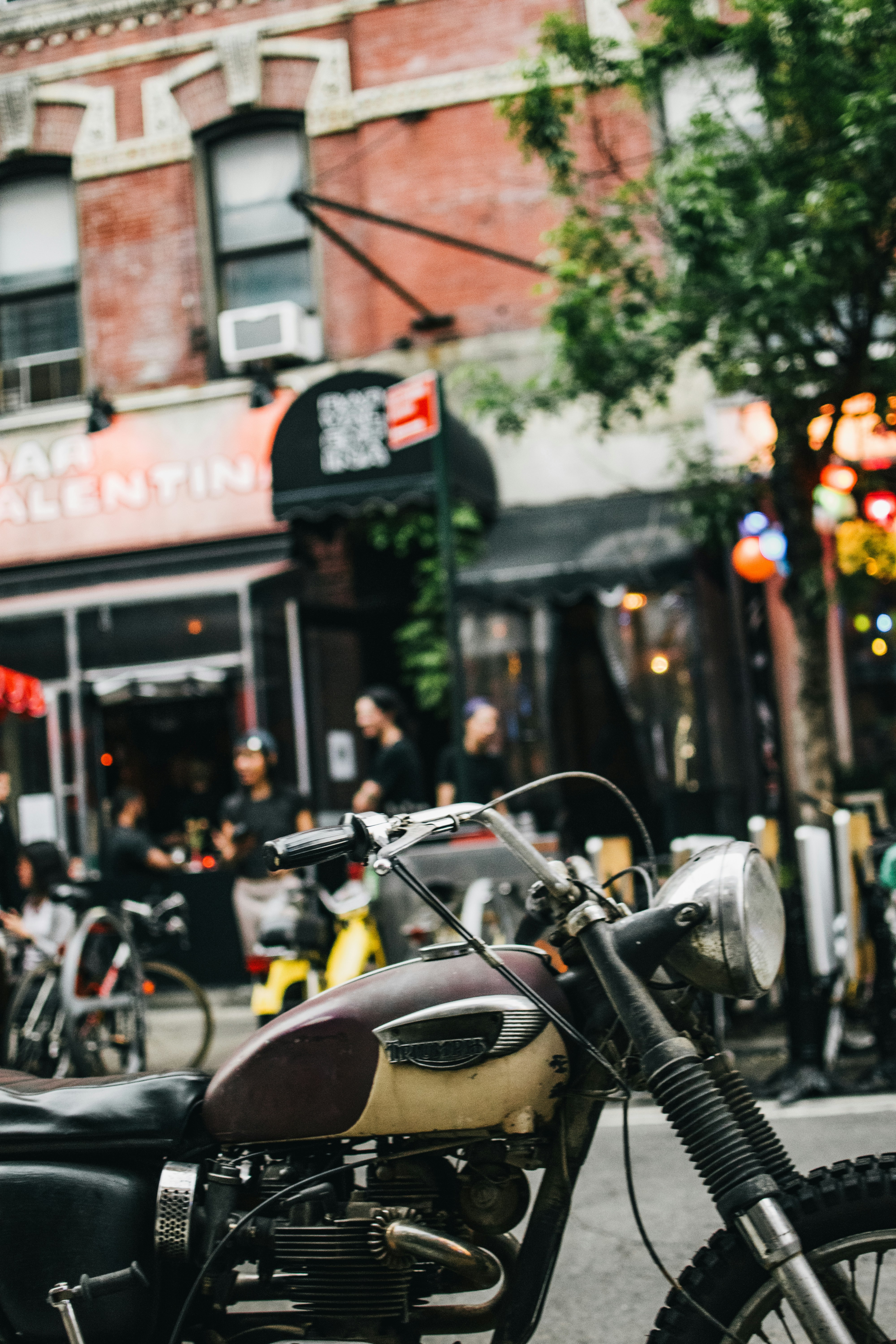 Vintage motorcycle parked on a city street with a cafe in the background