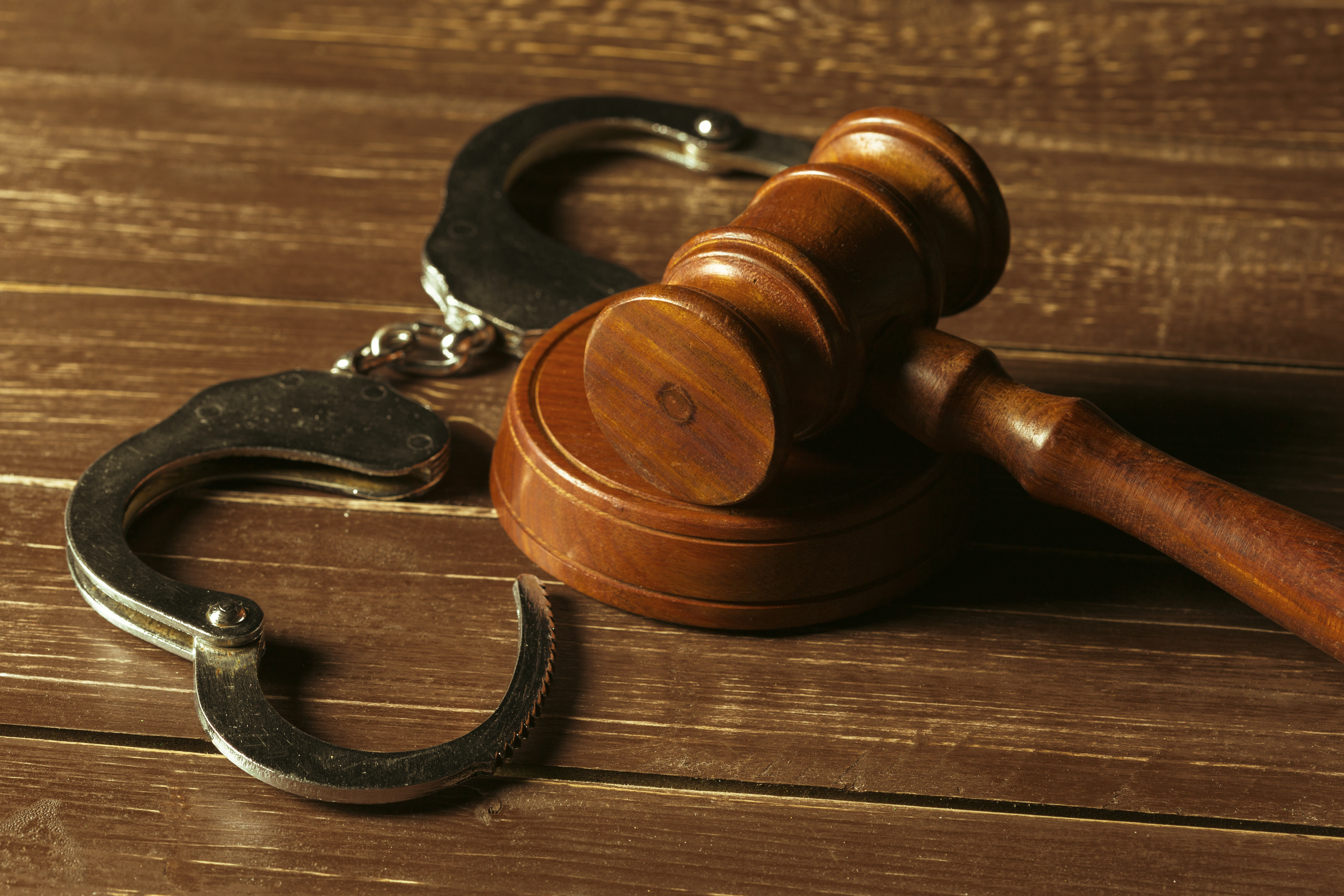 Judge's gavel and handcuffs on a wooden table
