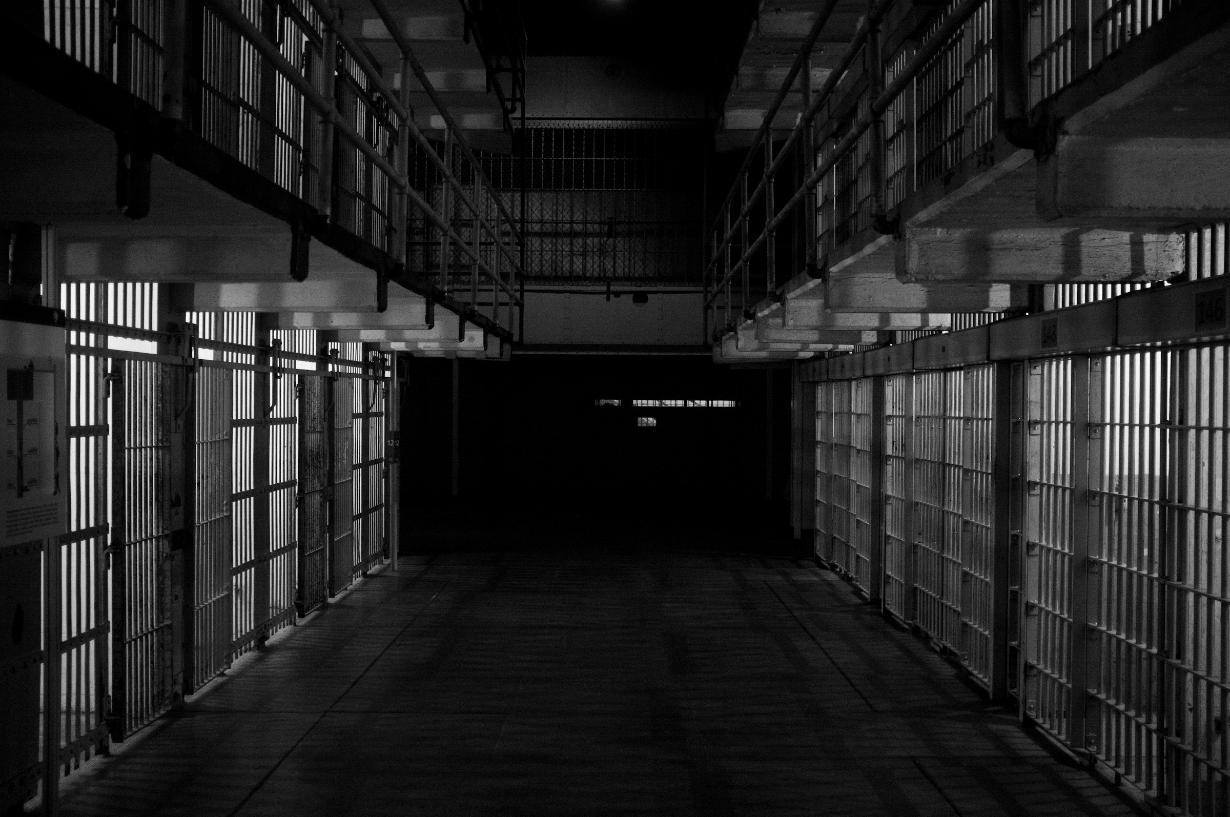 Dimly lit interior of a prison cell block with barred cells