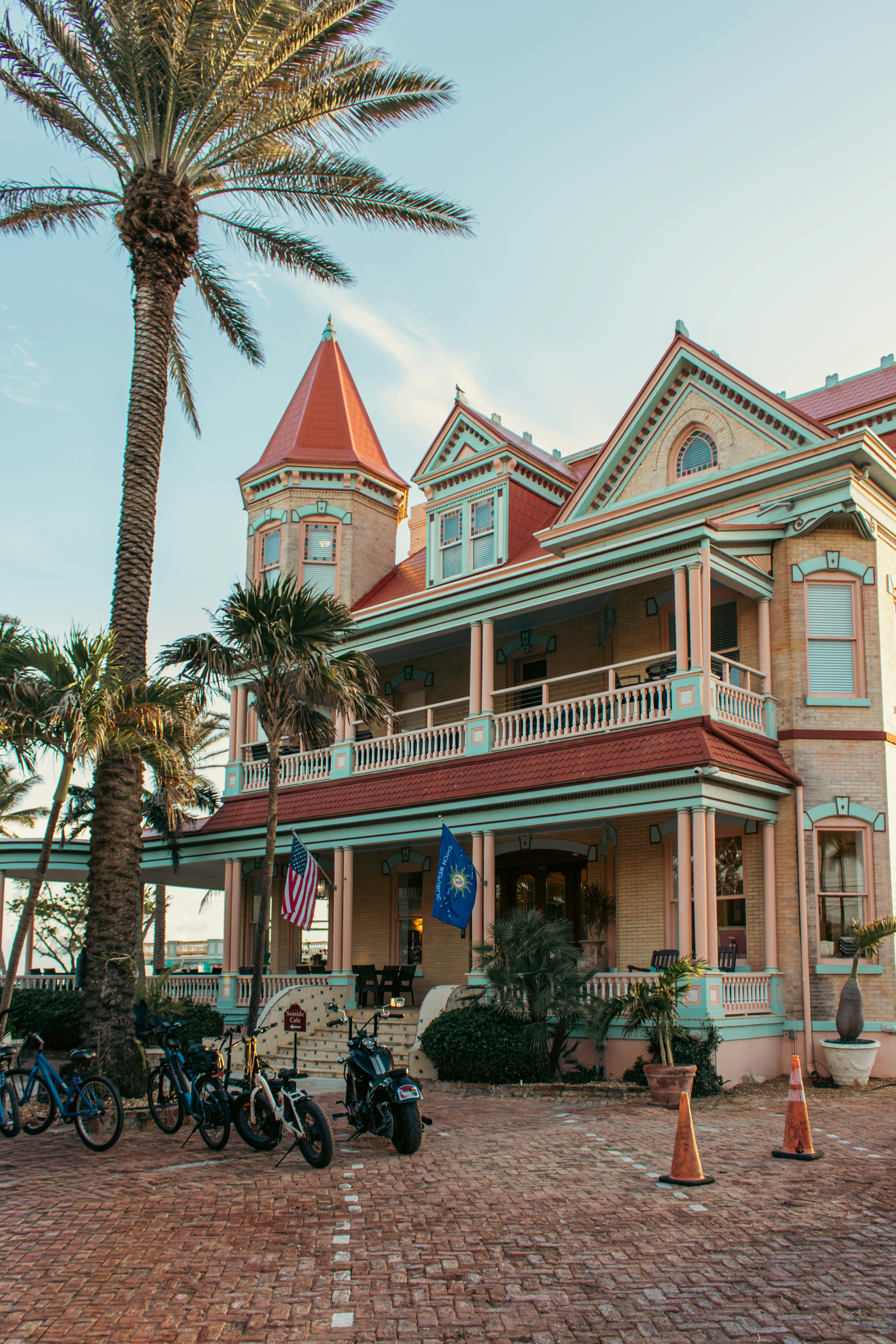 Historic Victorian-style building with palm trees and bicycles in front.