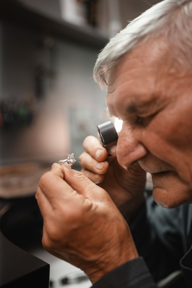 Elderly man examining a diamond with a magnifying glass