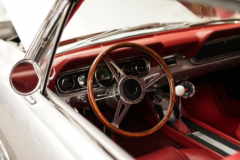 Interior of a vintage car with a wooden steering wheel and red upholstery