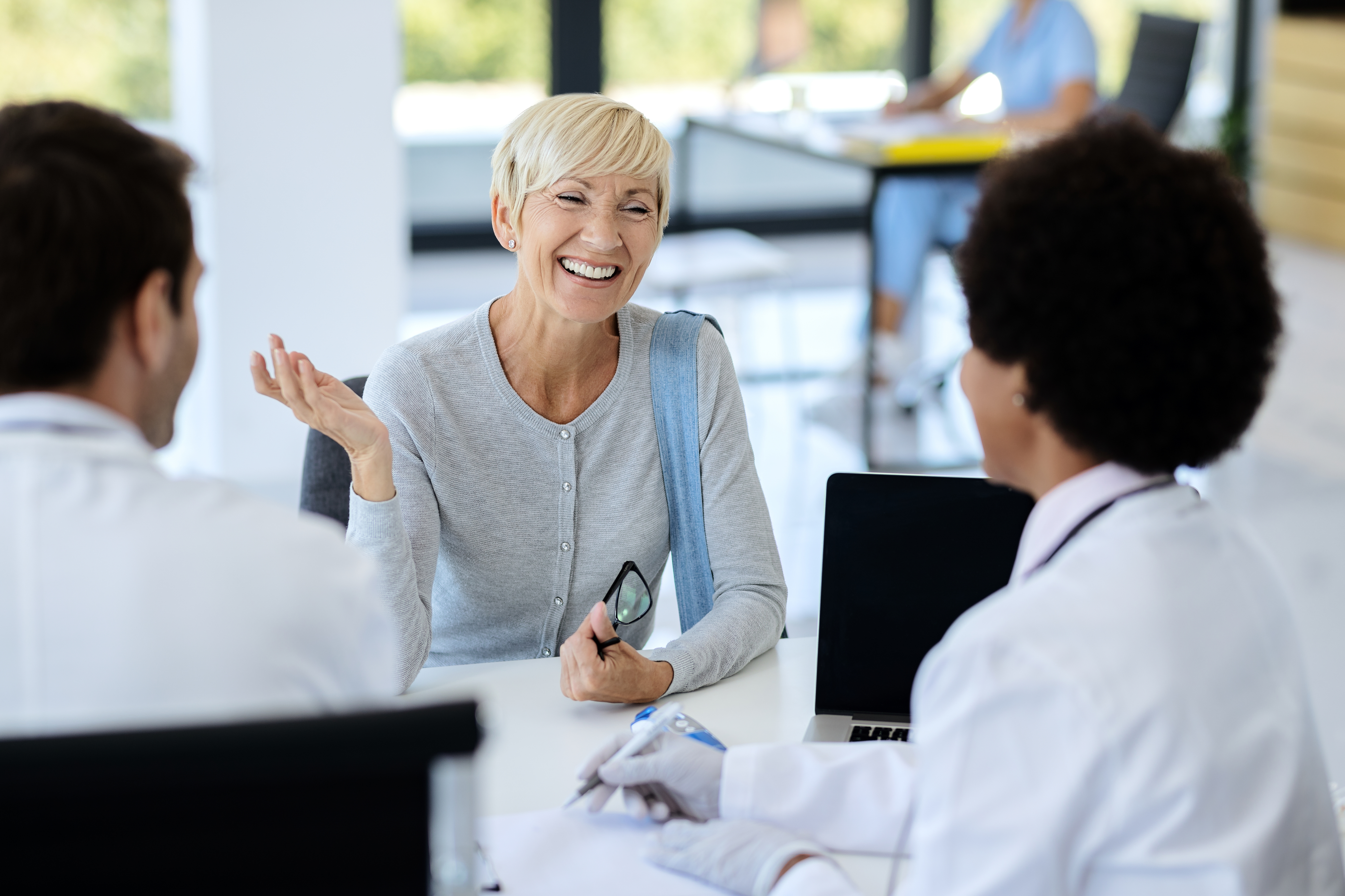 Smiling woman discussing with two professionals in an office setting