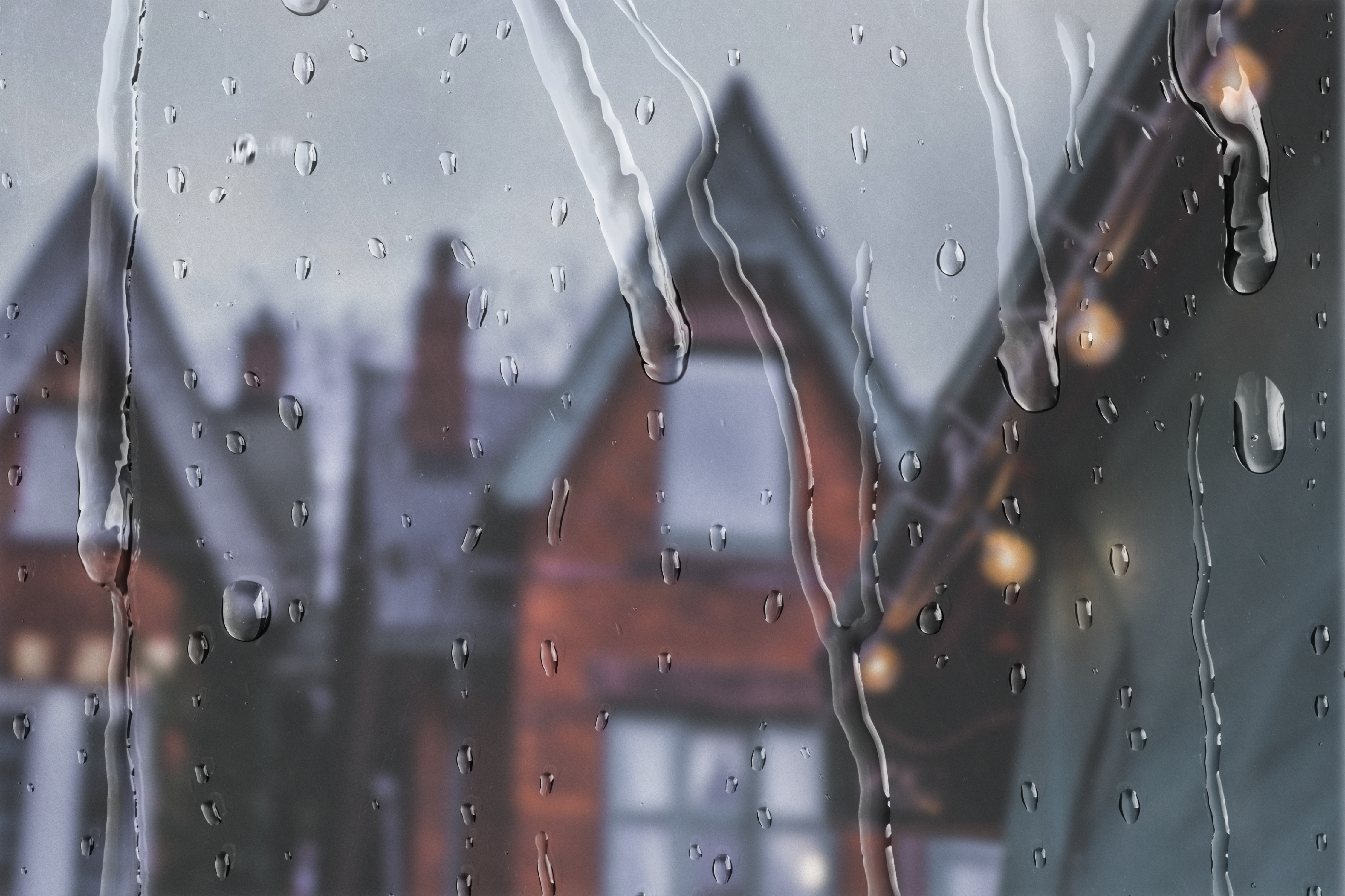 Raindrops on a window with blurred houses in the background