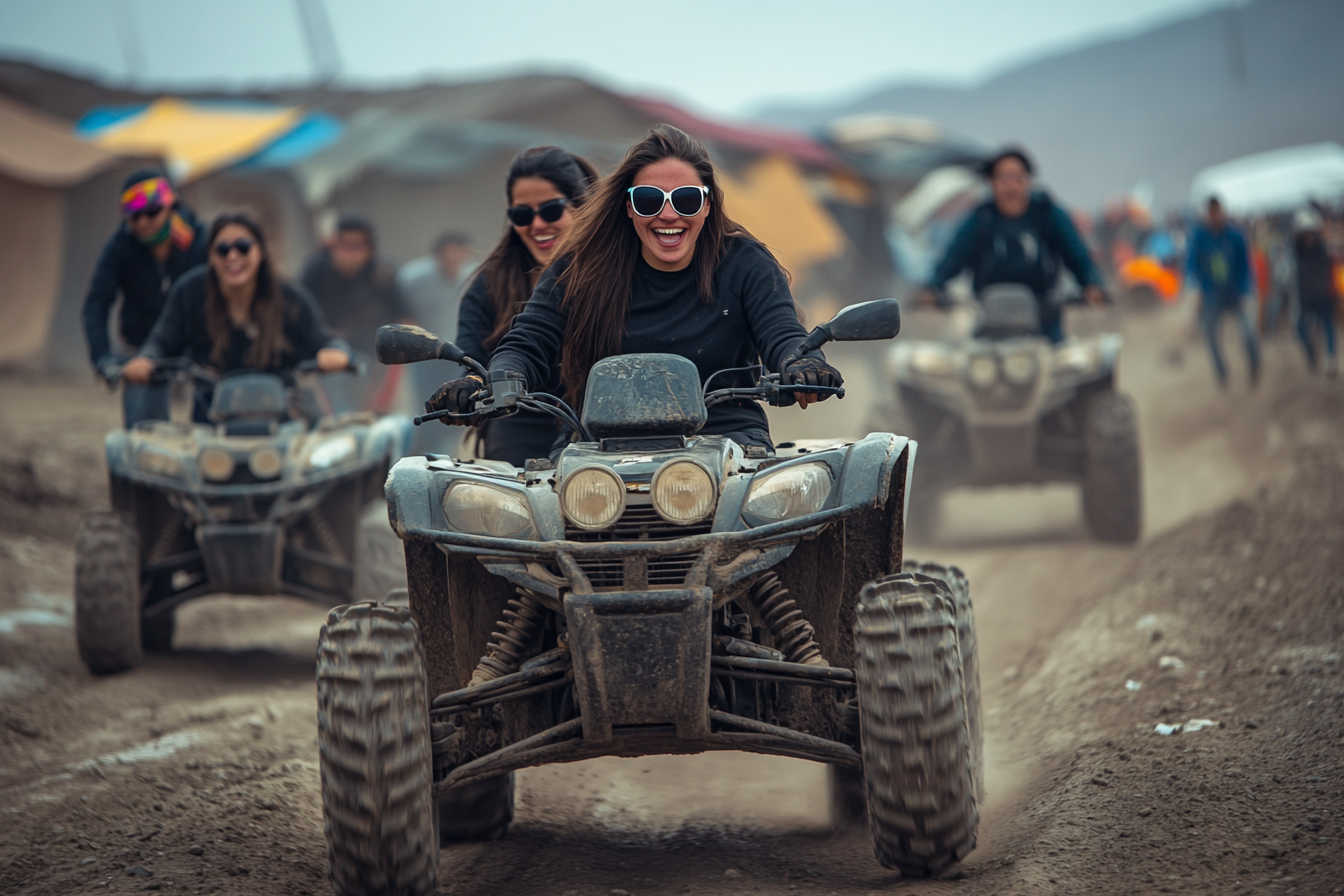 Group of people riding ATVs on a dirt path with tents in the background