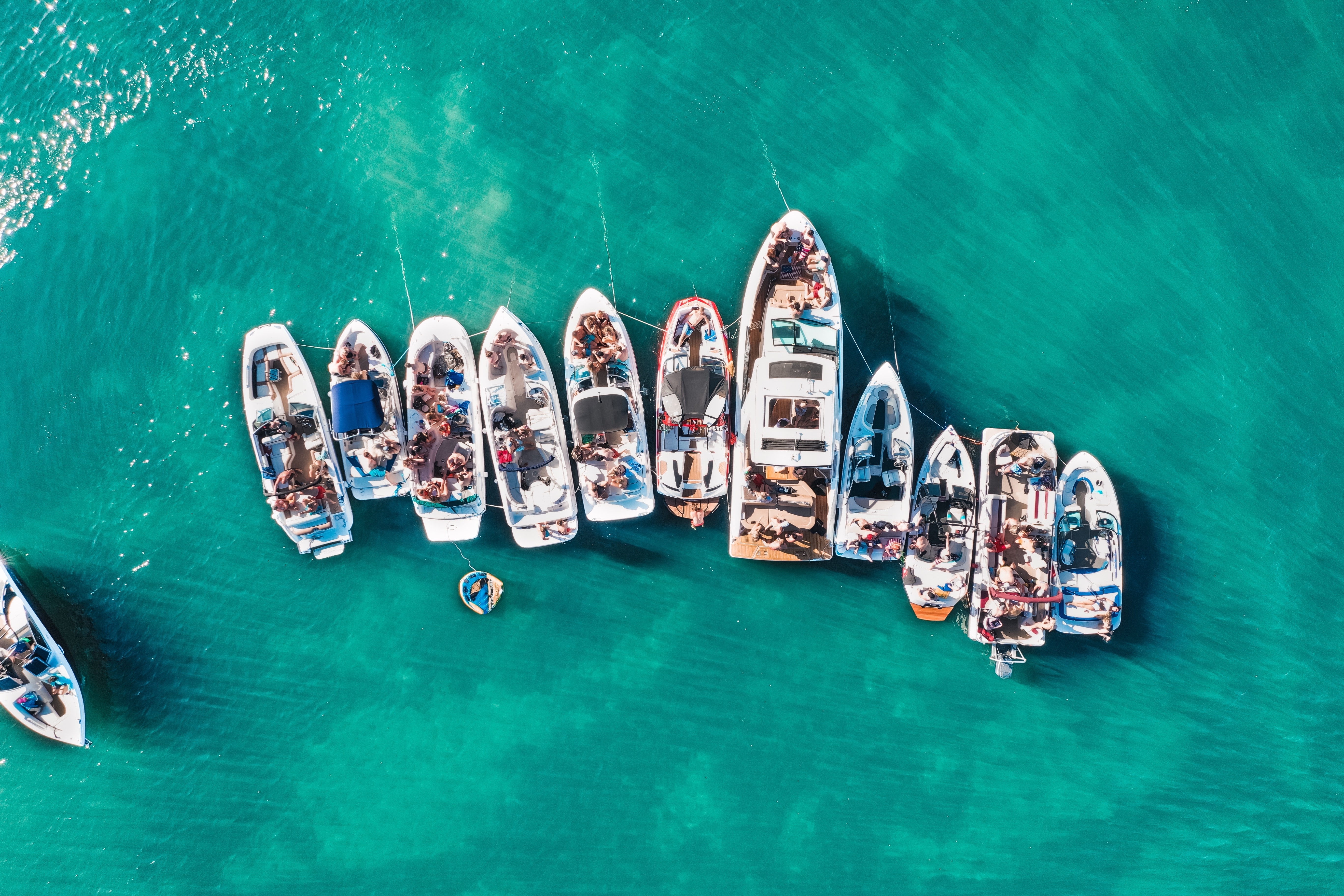 Aerial view of multiple boats anchored together on clear turquoise water