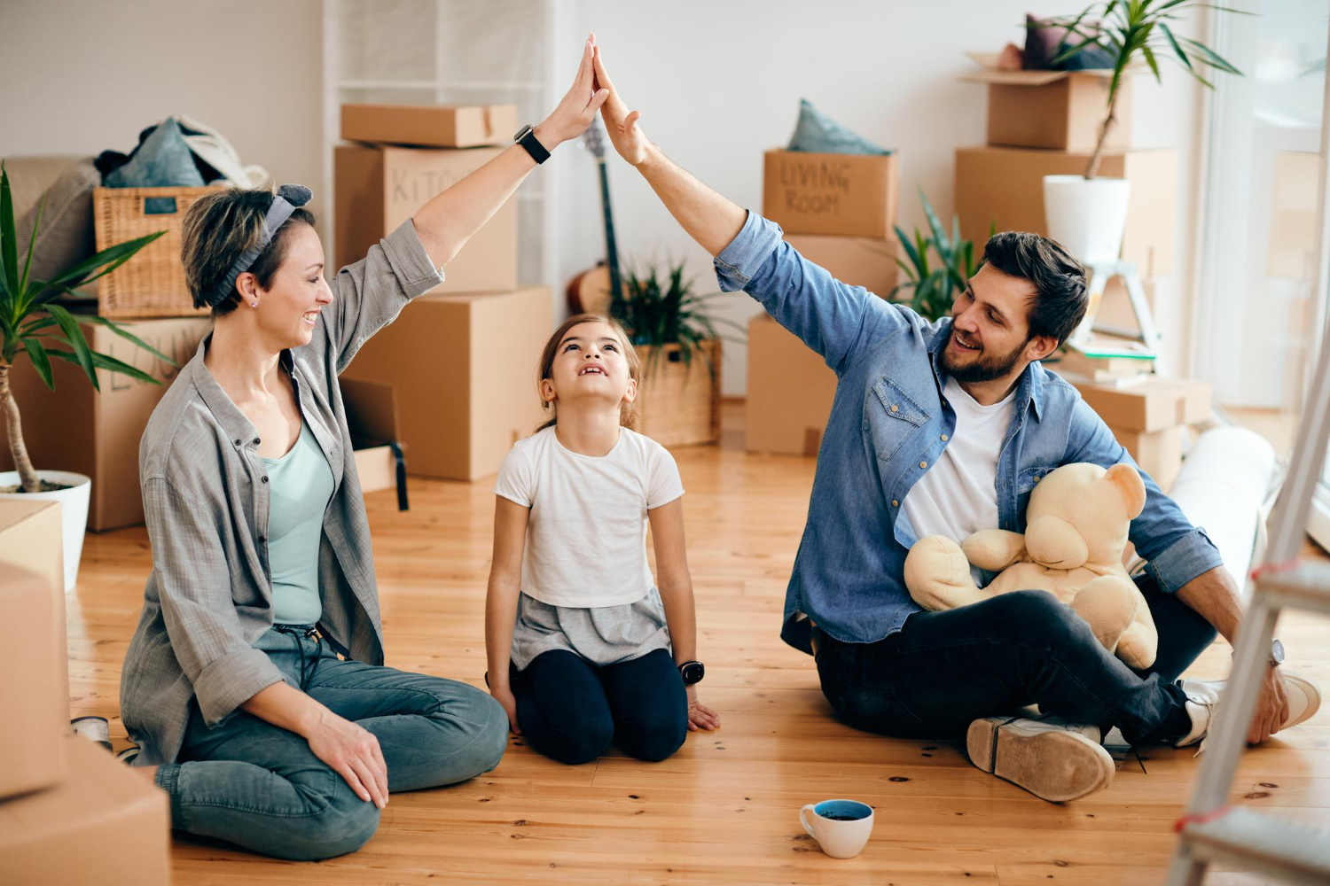 Family sitting on the floor surrounded by moving boxes, giving high-fives.