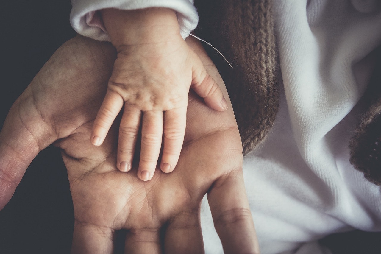 A woman is holding a wedding ring on her finger.