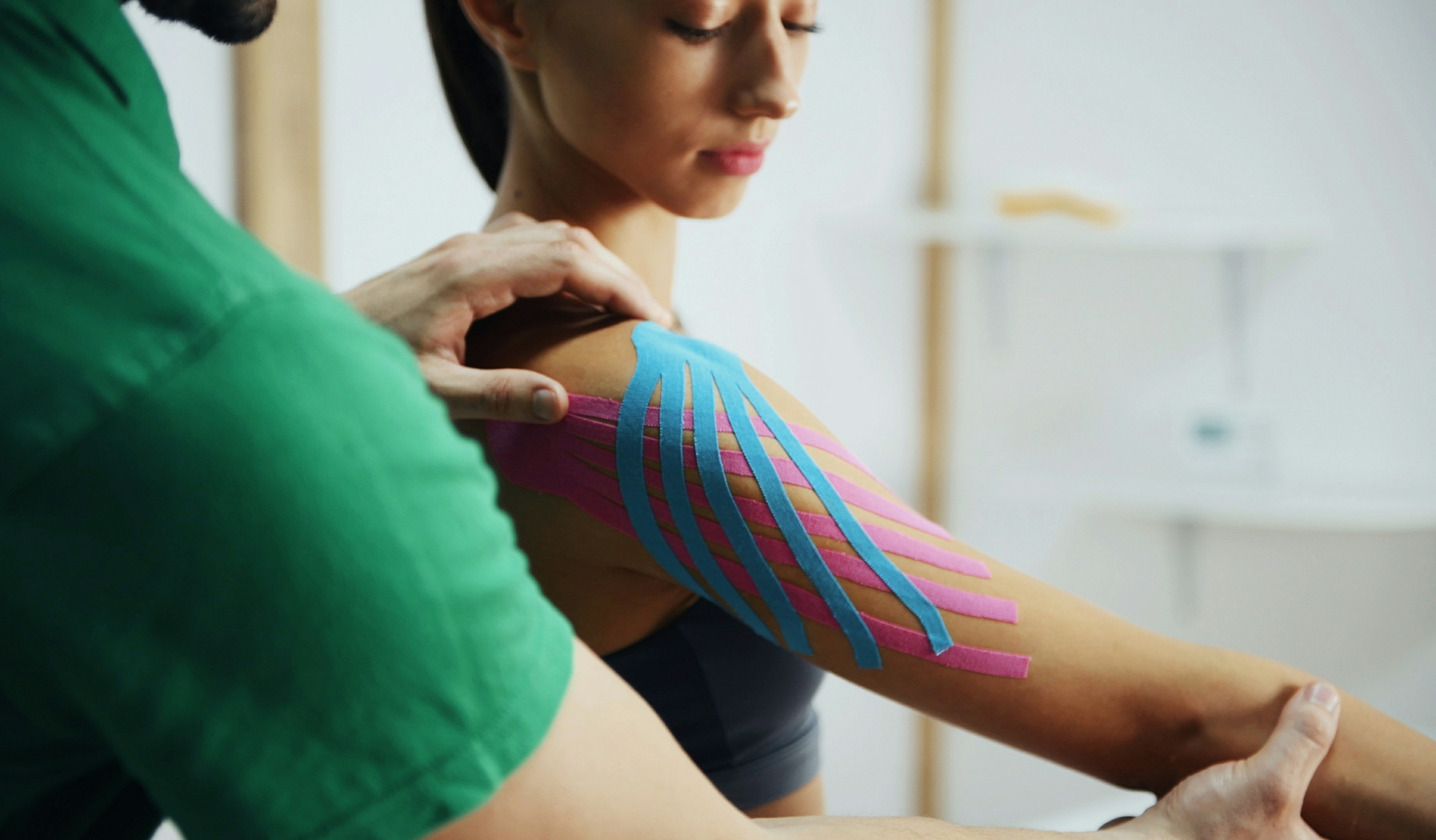 Physiotherapist applying kinesiology tape to a woman's shoulder