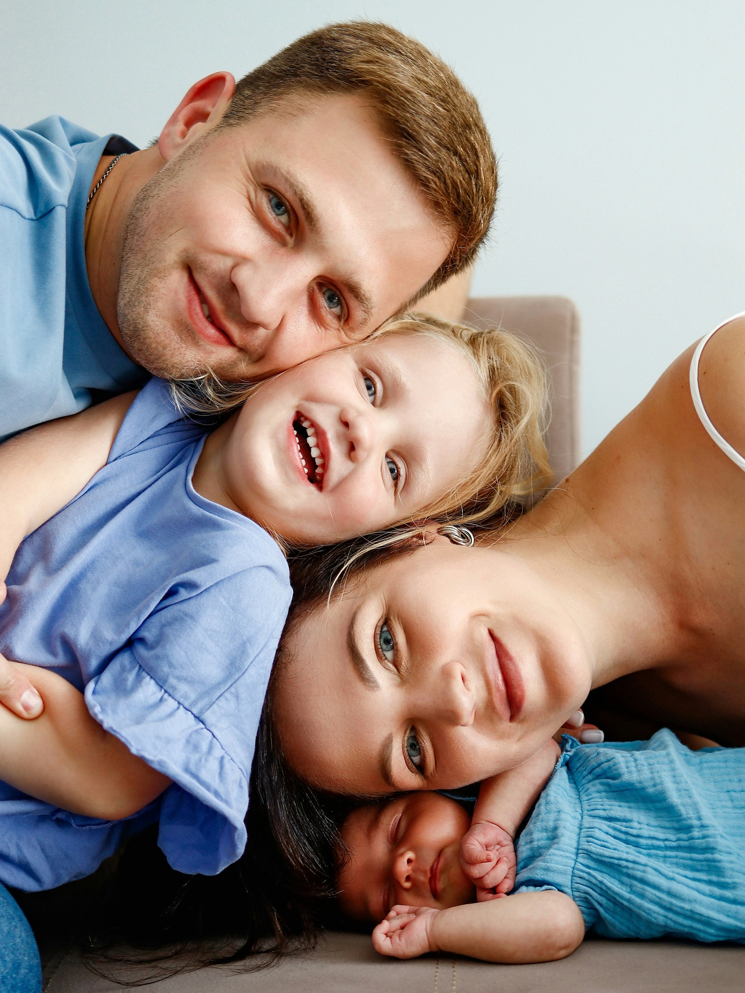 Family of four smiling and lying close together on a couch