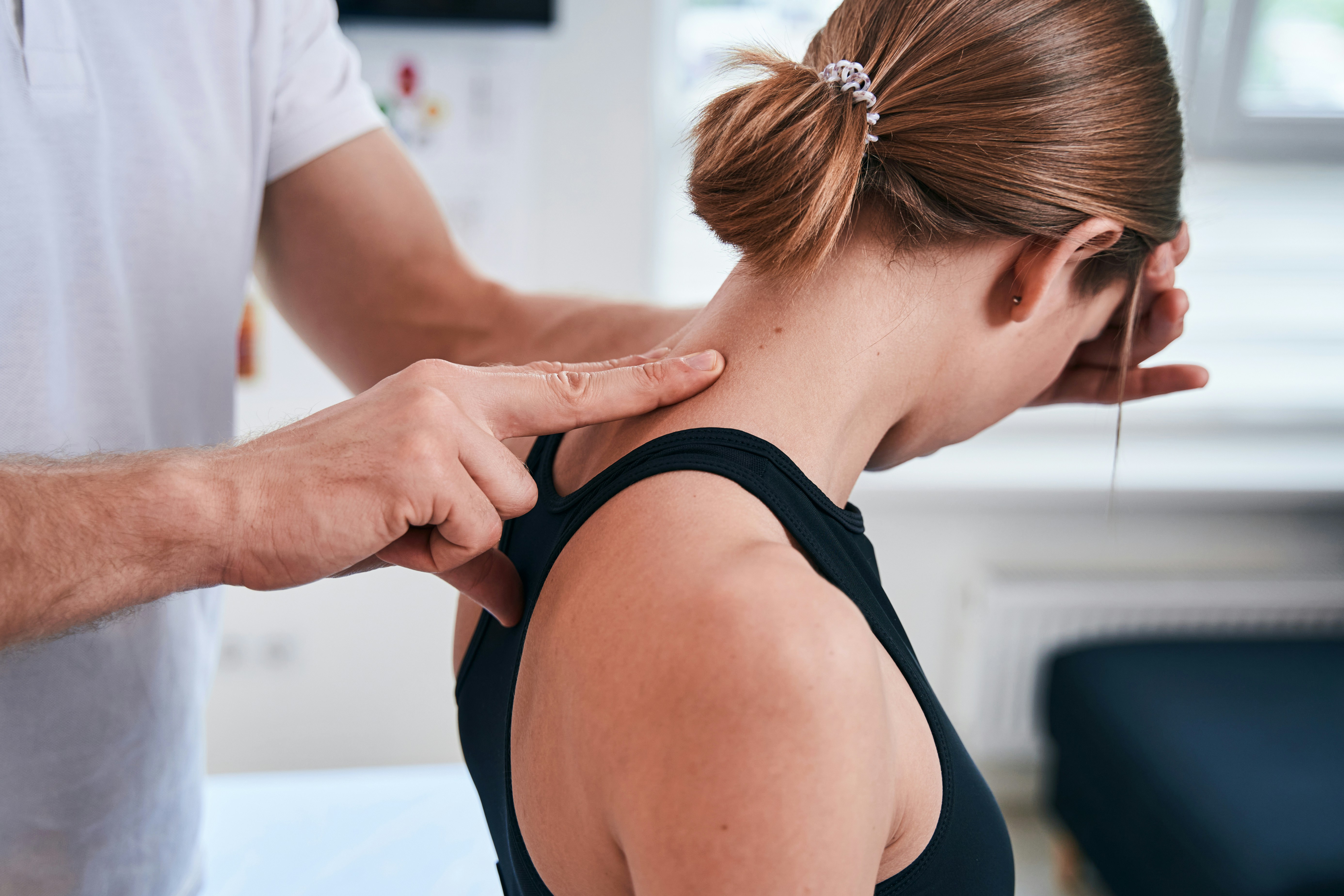 Chiropractor examining a woman's neck in a clinic