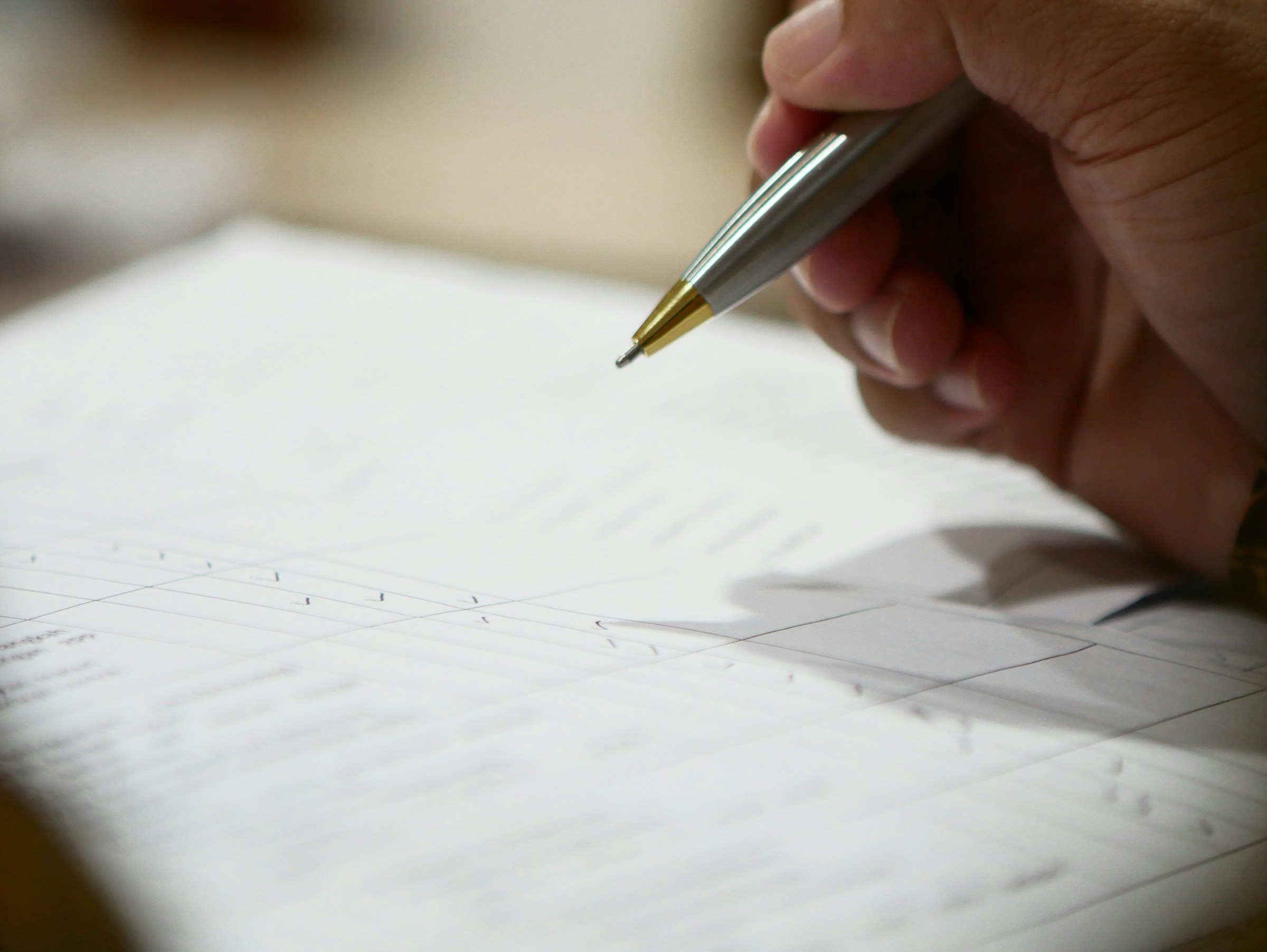 Close-up of a hand holding a pen over a document